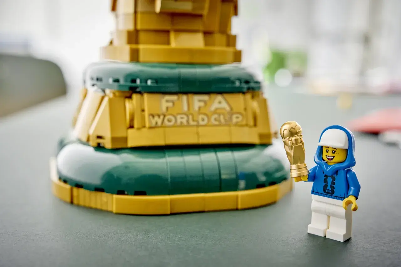 Ein Lego-Männchen mit FIFA-Hoodie hält stolz den goldenen Pokal des Lego World Cup.