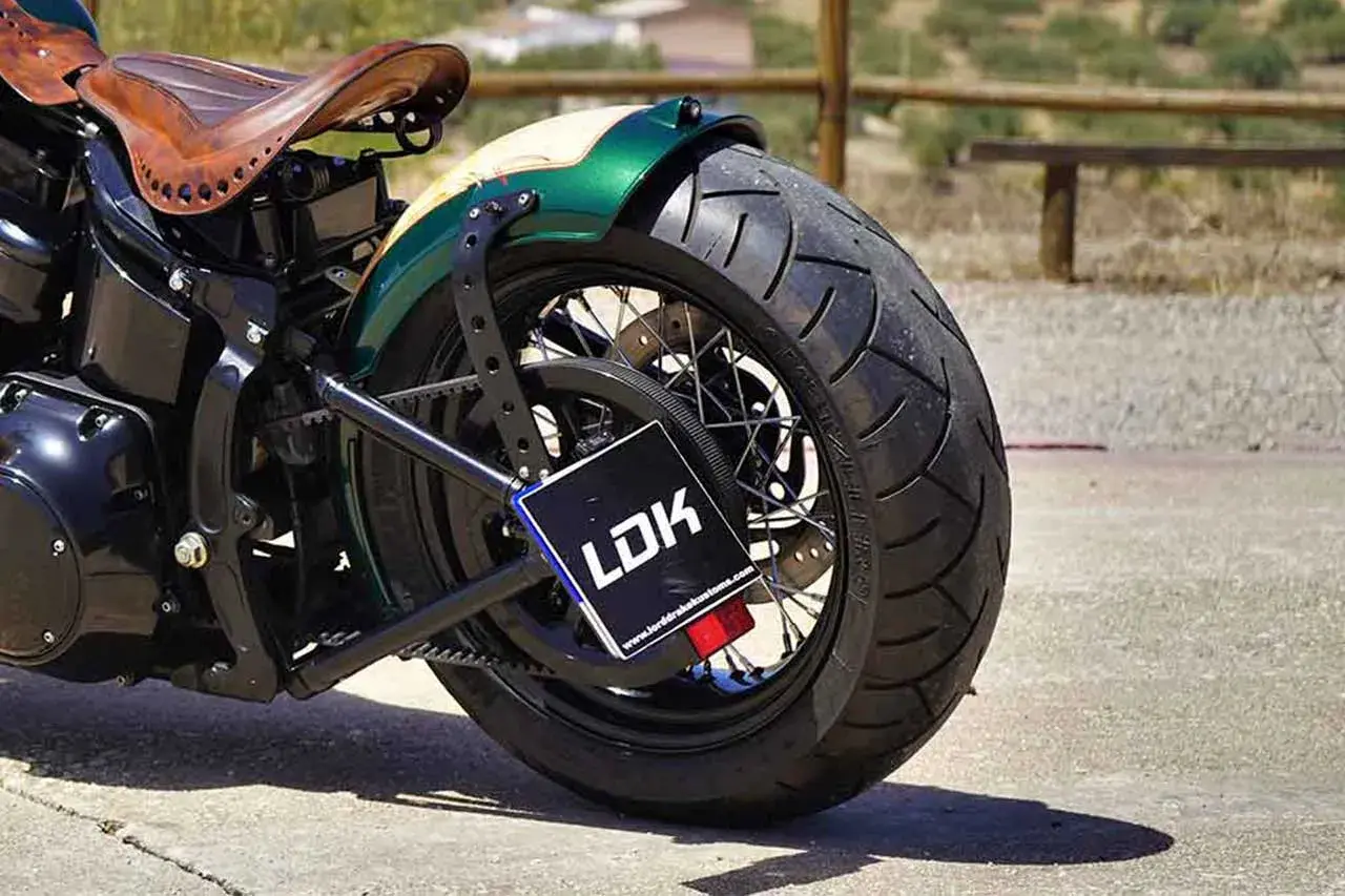 Detalle de moto customizada con asiento de cuero y guardabarros verde. La matrícula, con las medidas adecuadas, muestra el logo LDK.