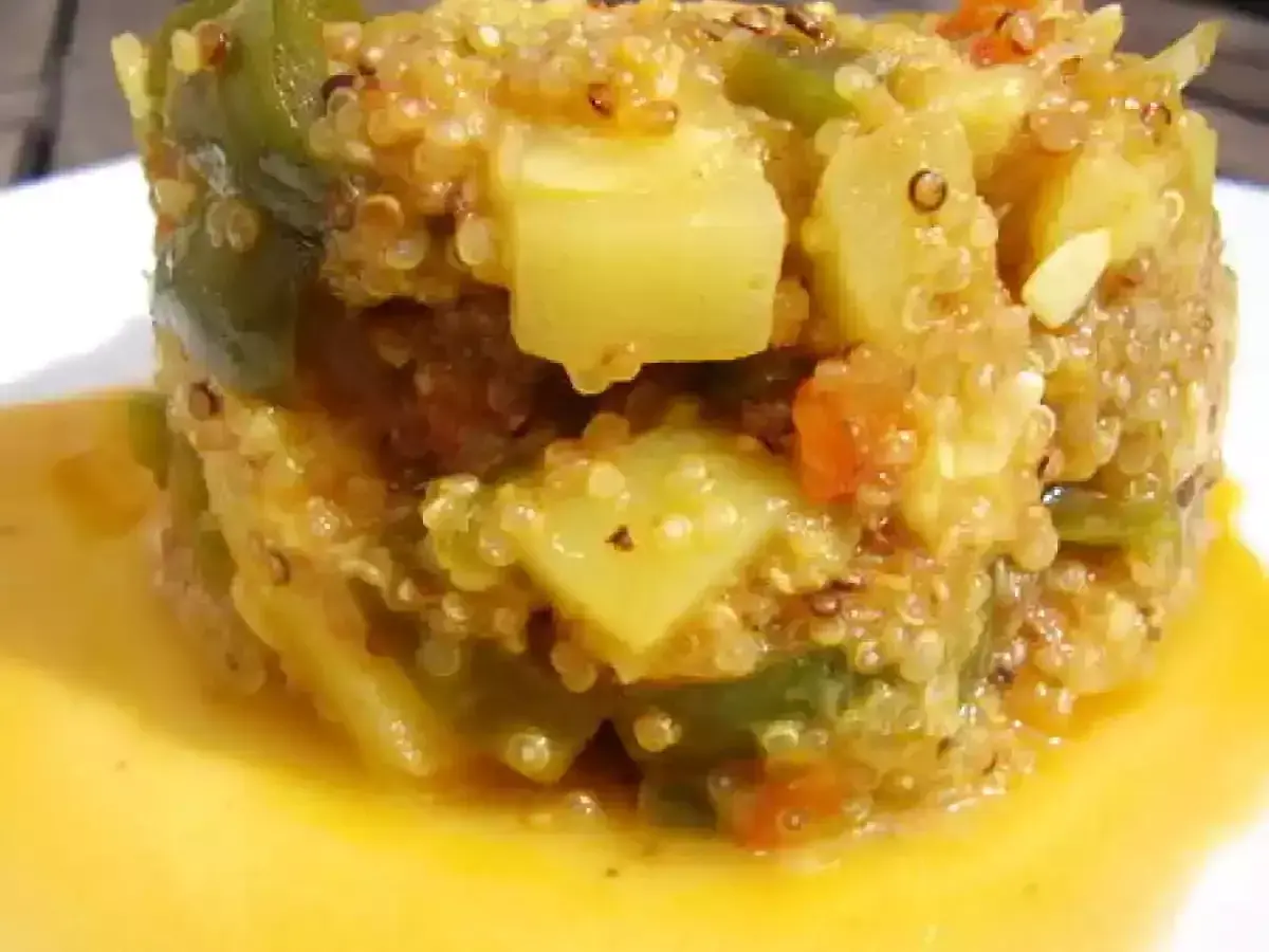Un délicieux risotto de quinoa aux légumes verts et tomates, servi dans une sauce dorée.