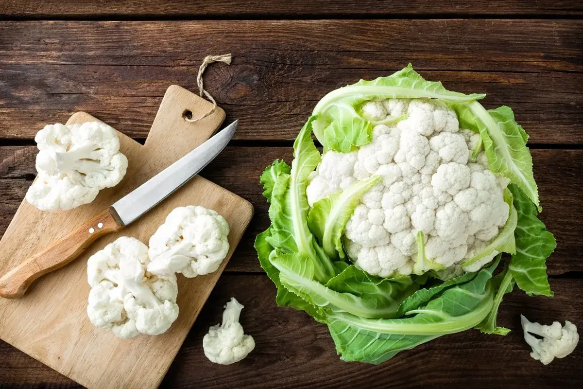 Świeży kalafior na drewnianym blacie. Zastanawiasz się, ile kalorii ma kalafior? To niskokaloryczne warzywo idealne na zdrową dietę.