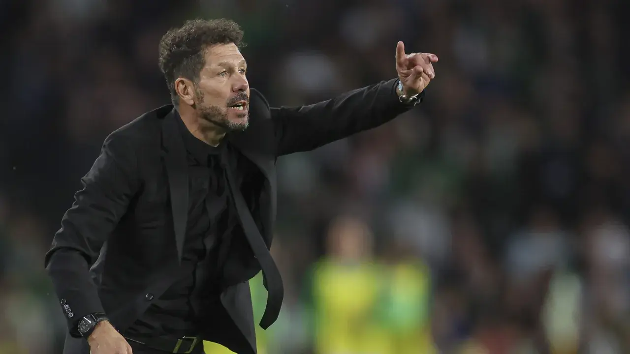 Cholo, trener Atletico Madryt, w czarnym garniturze gestykuluje na boisku, wskazując coś swoim zawodnikom.