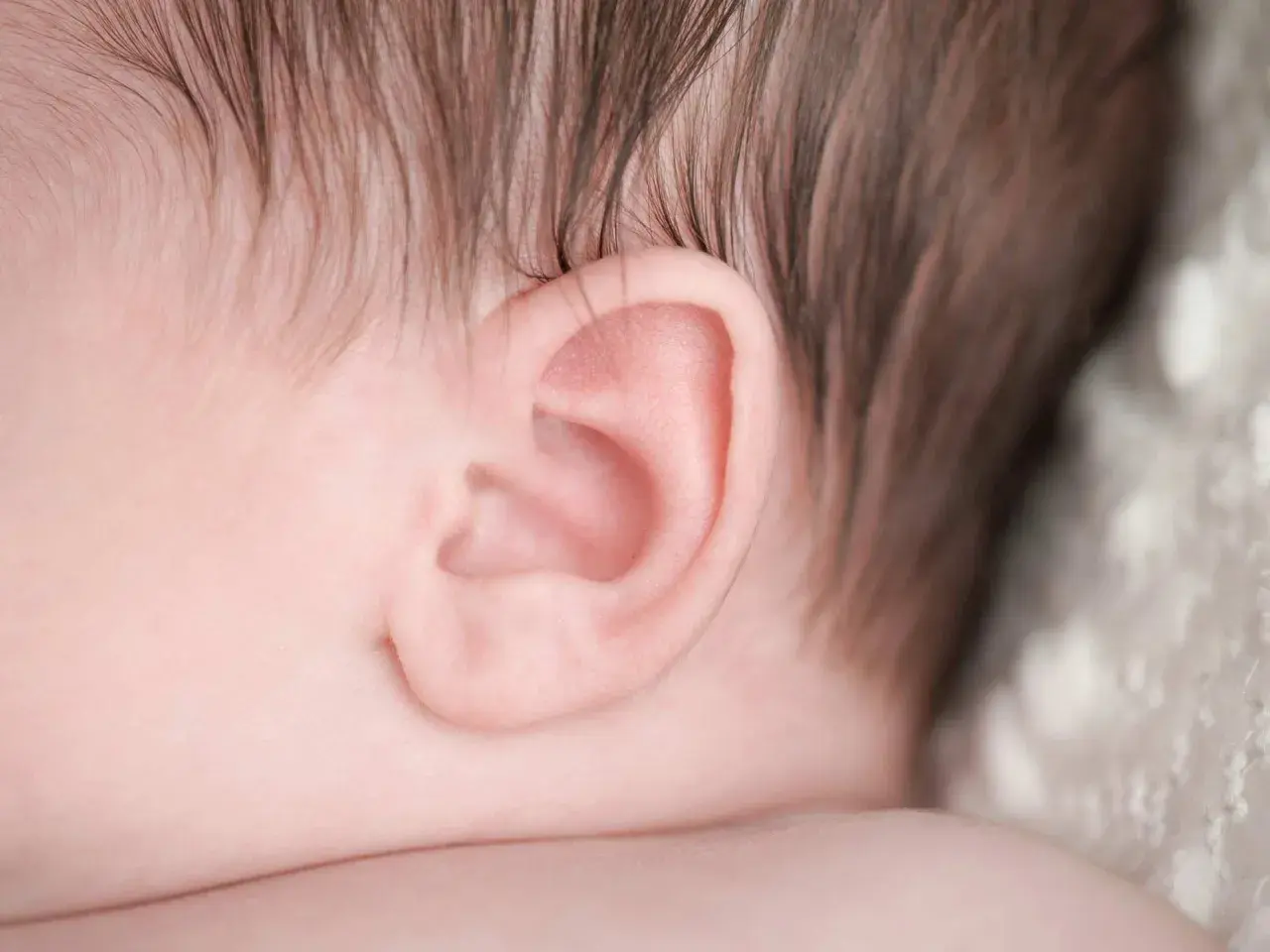 Primo piano dell'orecchio di un neonato, un dettaglio delicato che può essere interessato da otite nei bambini.