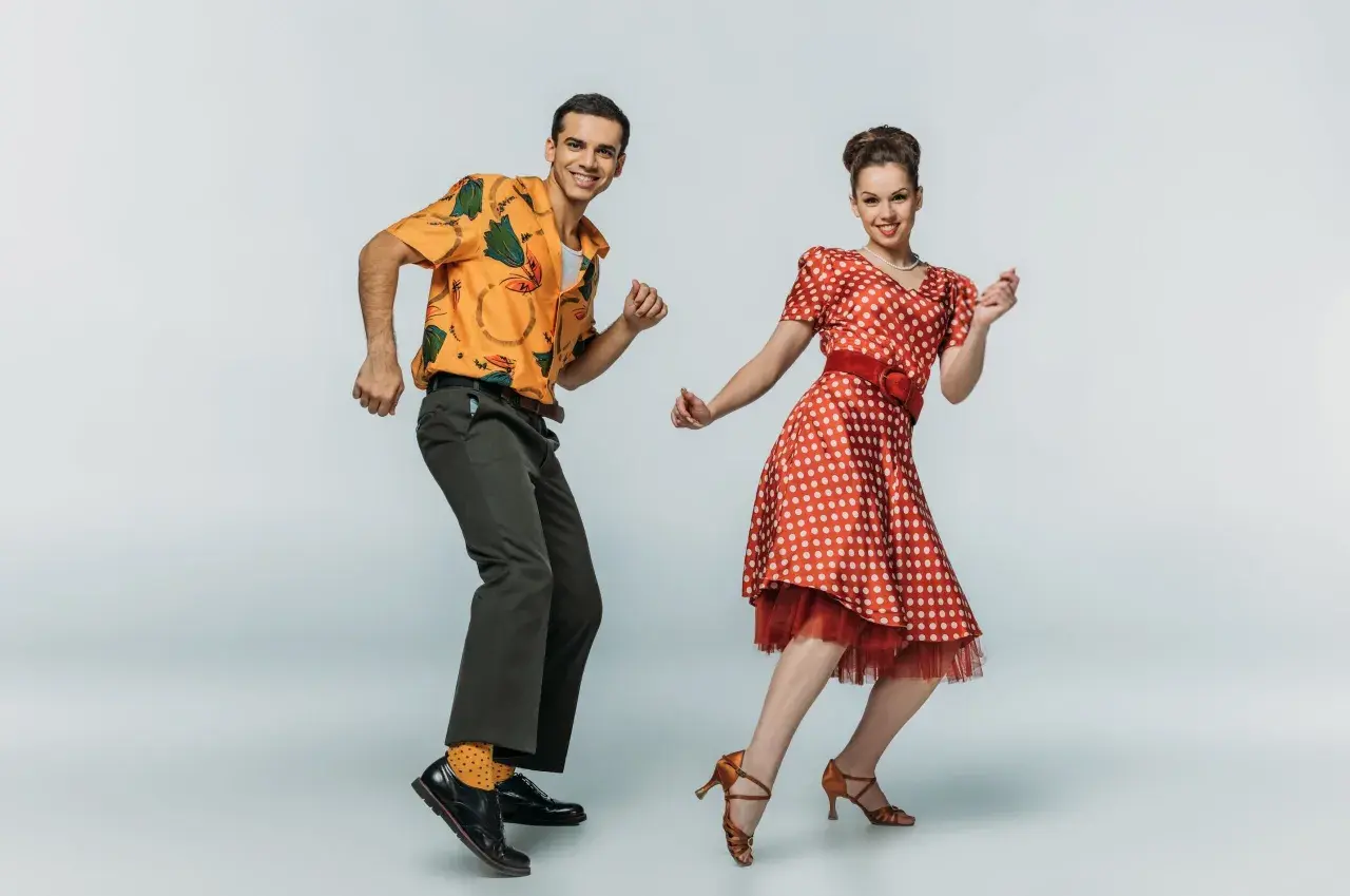 Coppia in abiti vintage che esegue boogie woogie passi e figure con gioia.