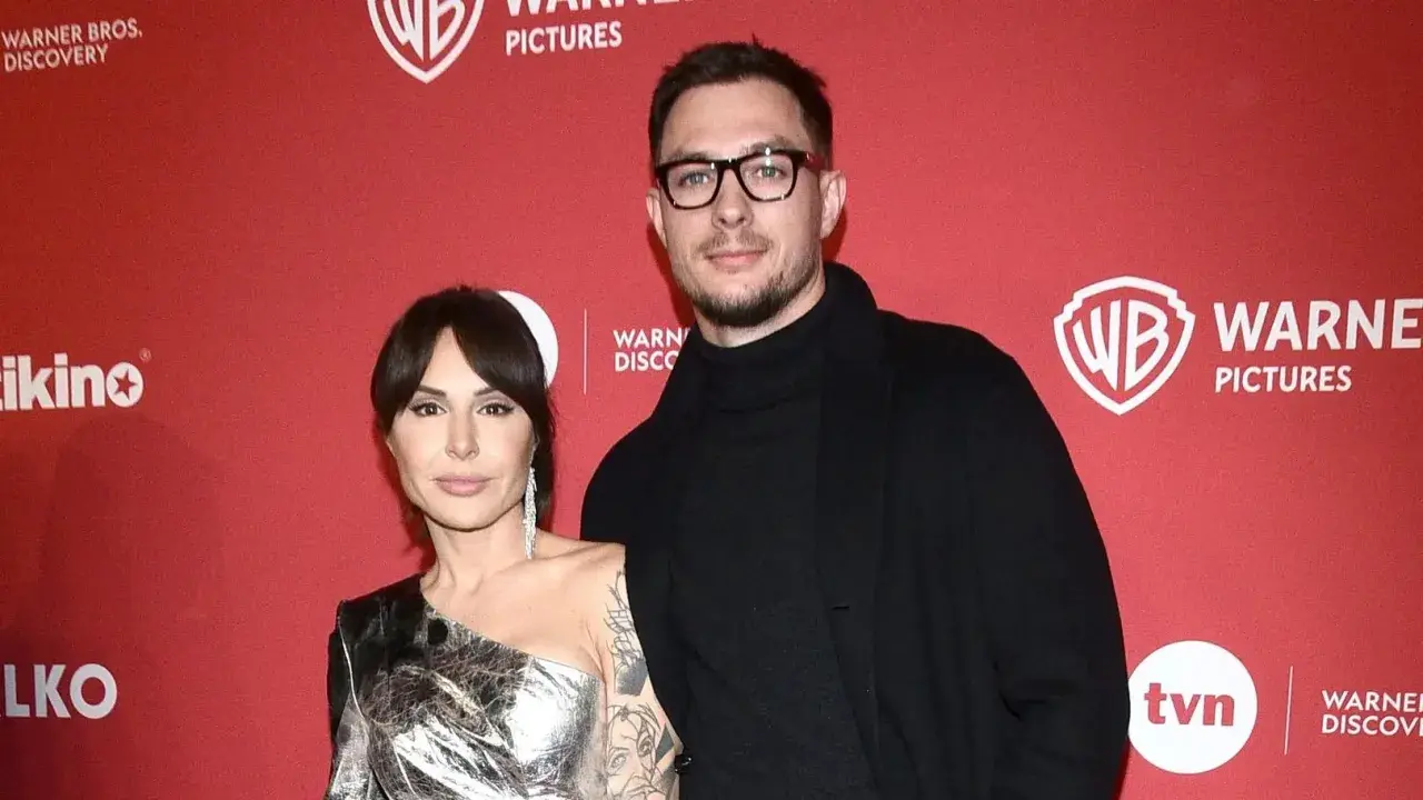 Blanka Lipińska z partnerem na czerwonym tle z logo Warner Bros. Pictures.