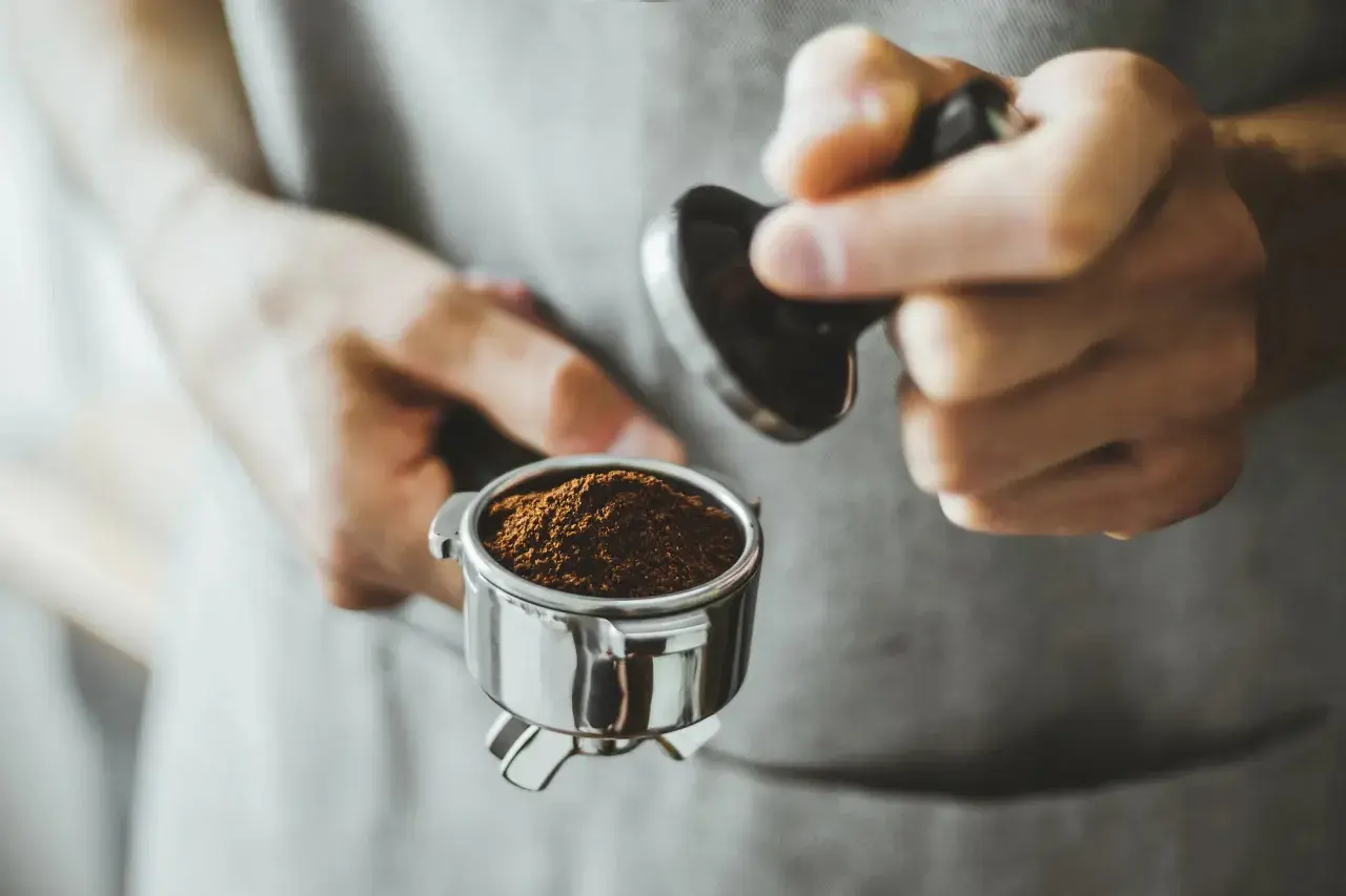Barista tamped den frisch gemahlenen Kaffee für einen perfekten Kaffee shot.