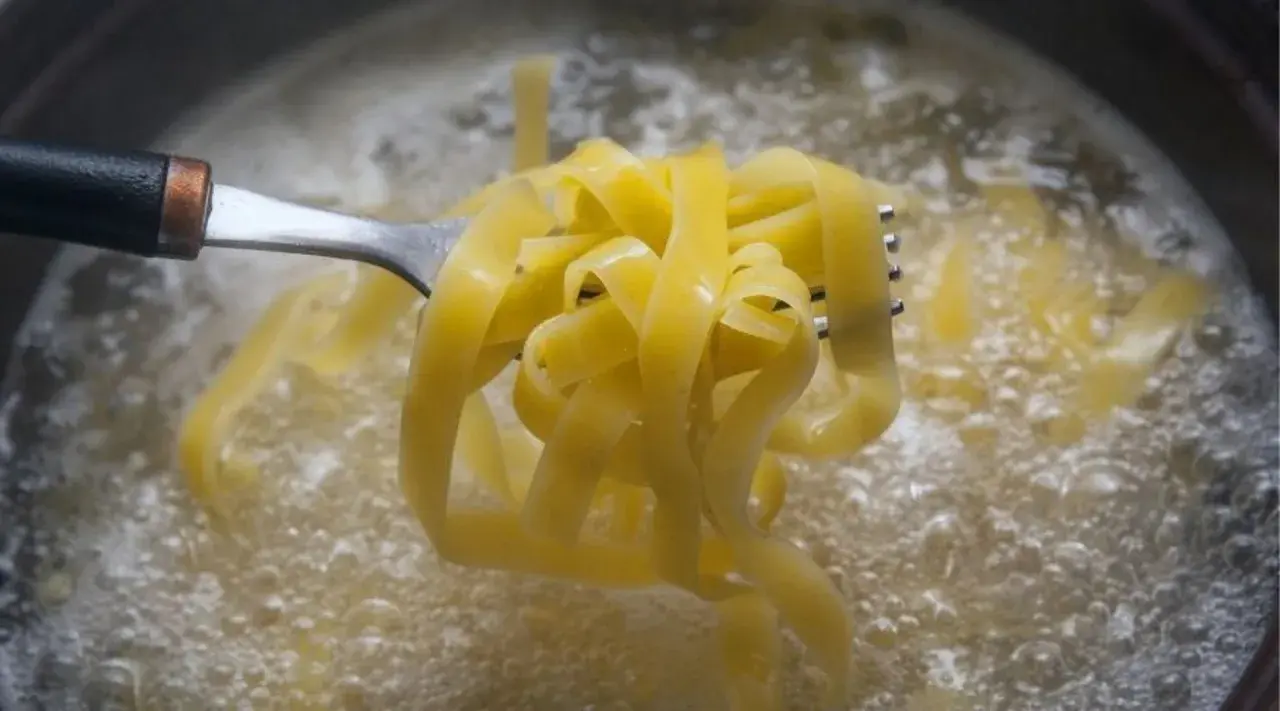 Tagliatelle na widelcu unoszone z wrzącej wody. Prosty sposób, jak ugotować makaron do perfekcji.