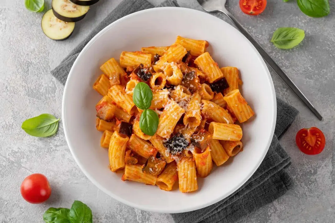 En skål med pasta norma, en klassisk siciliansk rätt med aubergine och tomatsås, toppad med basilika och parmesan.