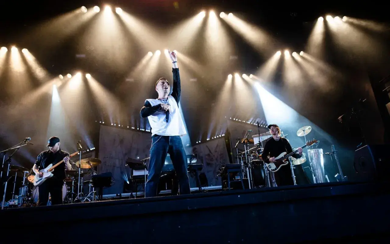 Oskar Linnros konsert med bandet upplyst av starka strålkastare. Sångaren med mikrofonen i handen och en arm uppsträckt.