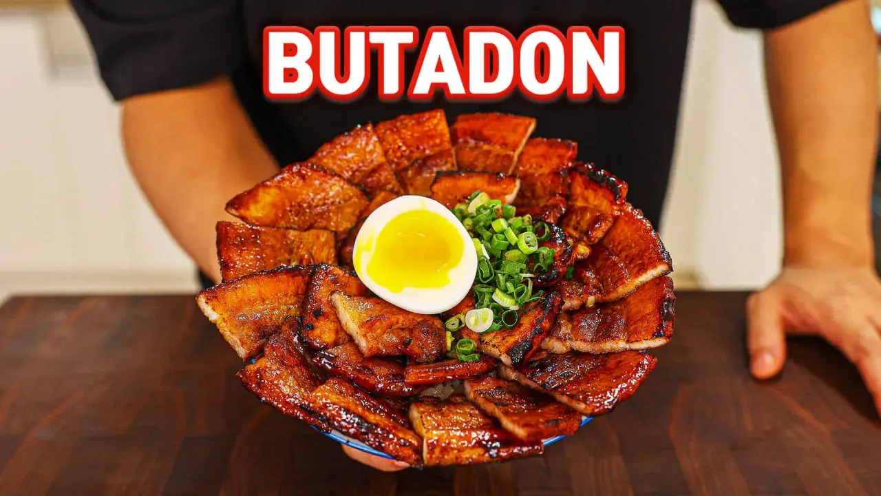 A generous serving of glistening pork donburi, topped with a perfectly soft-boiled egg and chopped green onions.
