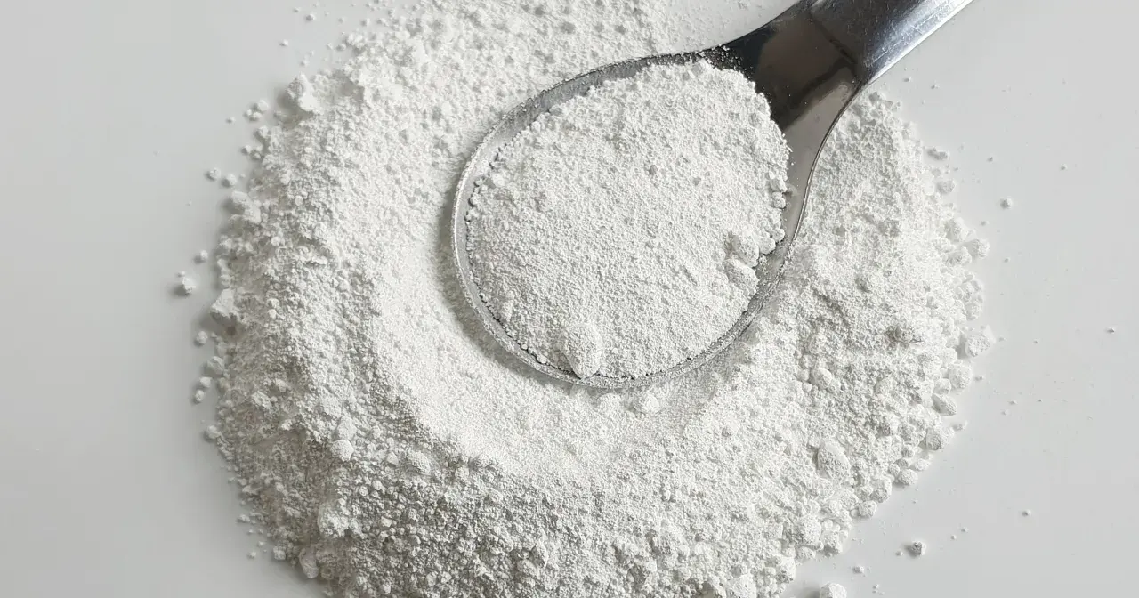 Biały proszek na łyżce i rozsypany na powierzchni. Czy to potencjalna **titanium dioxide szkodliwość**?