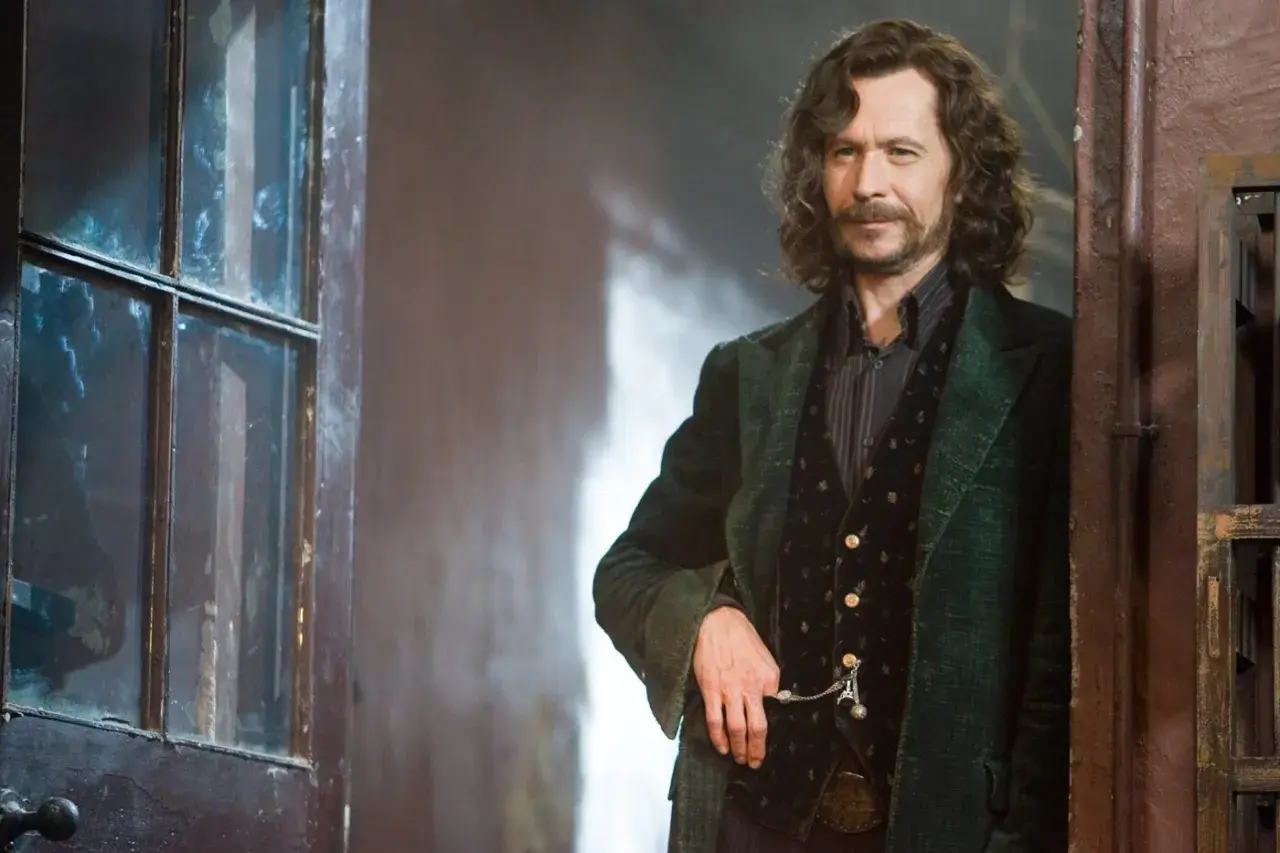 Gary Oldman jako Syriusz Black w Harry Potterze, stojący obok drzwi z szybą.