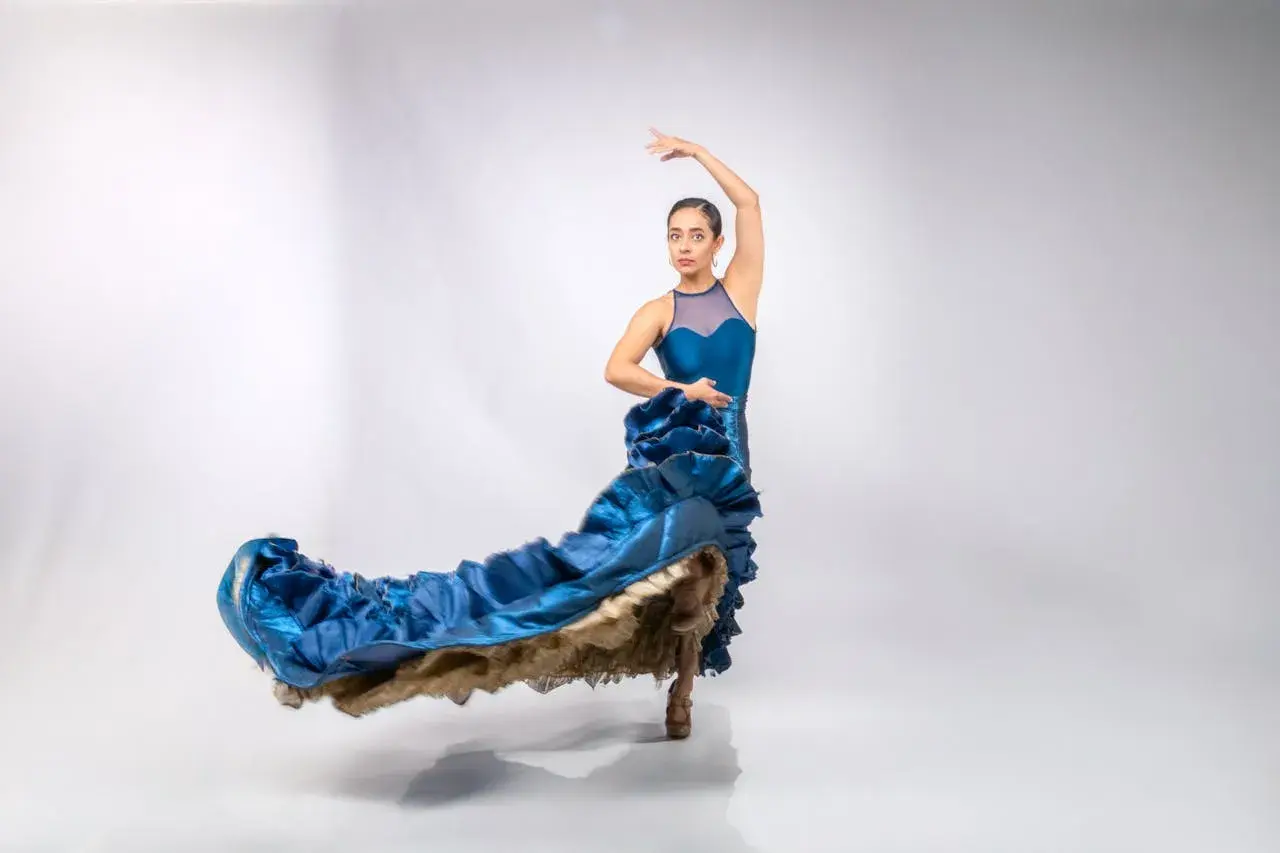 Bailarina con vestido azul ondeante, capturando la pasión y el arte de donde viene el flamenco.