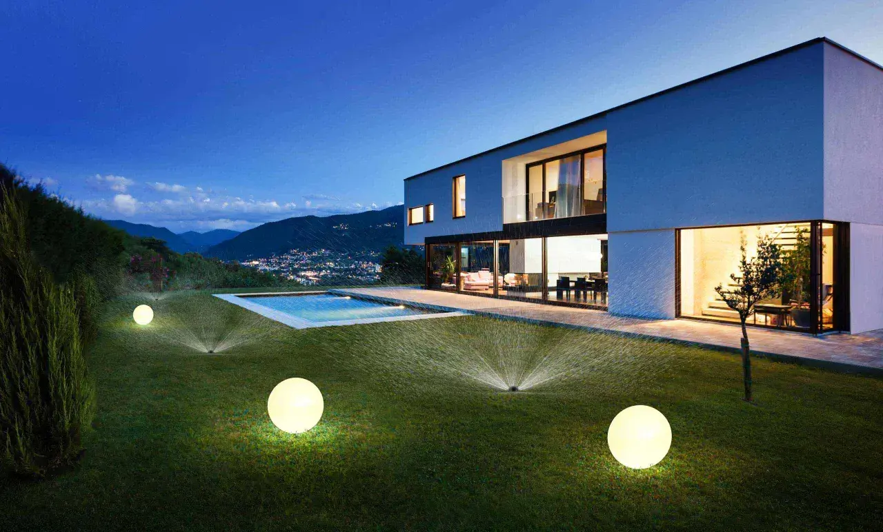 Modern villa con piscina iluminada y aspersores automáticos, un ejemplo de ideas domotica para un jardín perfecto.