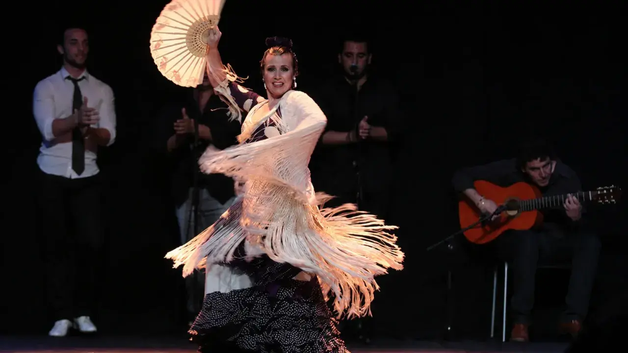 Bailaora con abanico y mantón, evocando el espíritu de Lorca y el flamenco, acompañada por guitarrista y palmeros.