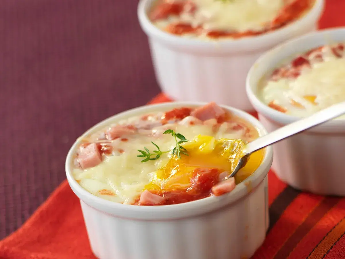 Œufs cocotte au four, jambon et fromage fondus, un délice crémeux prêt à être dégusté.