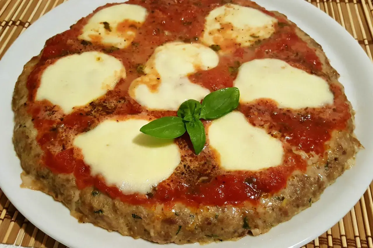 Bistecche alla pizzaiola con mozzarella filante e basilico fresco, un piatto gustoso e invitante.