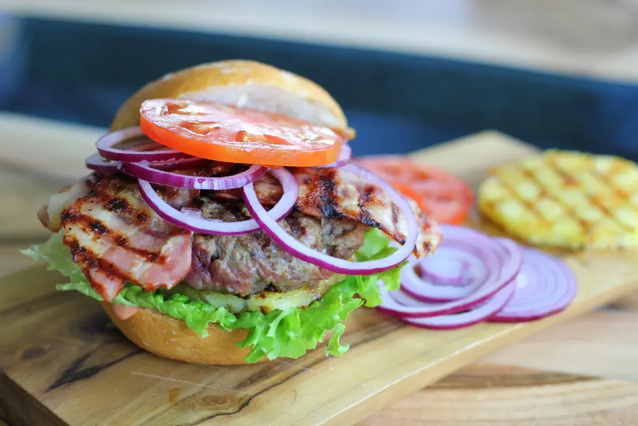 Pyszny burger z bekonem, sałatą, pomidorem i cebulą. Idealny przykład, jak składac burgera, by był soczysty i pełen smaku.