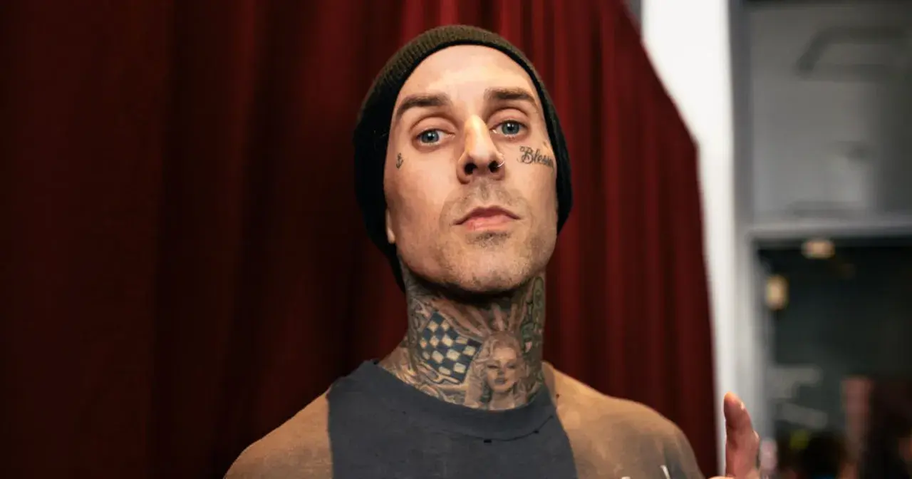 Travis Baker w czarnej czapce beanie, z tatuażami na twarzy i szyi, w tym wizerunkiem Marilyn Monroe.
