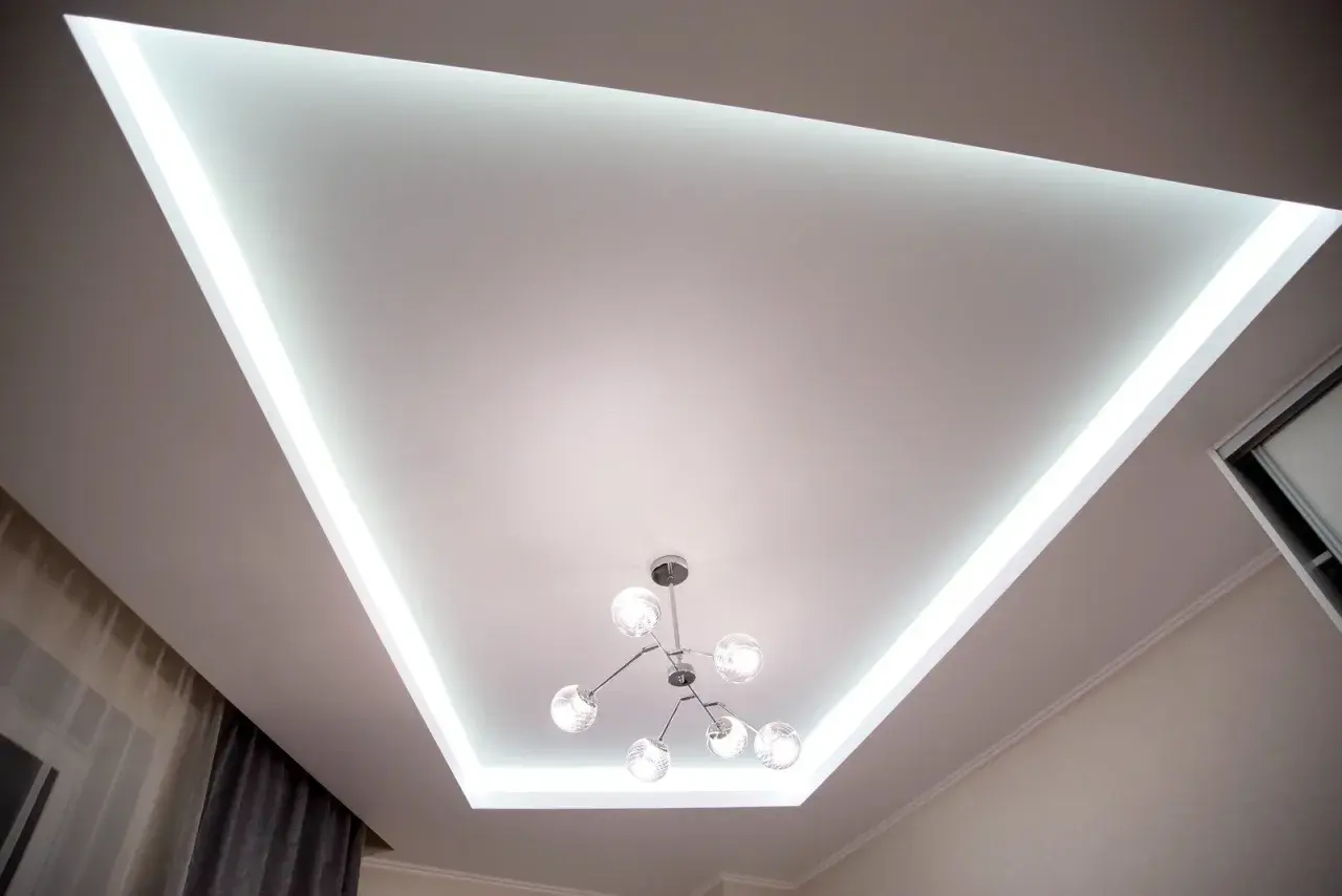 Nowoczesny sufit napinany z podświetleniem LED tworzy niepowtarzalne inspiracje dla wnętrz. Stylowa lampa dodaje elegancji.