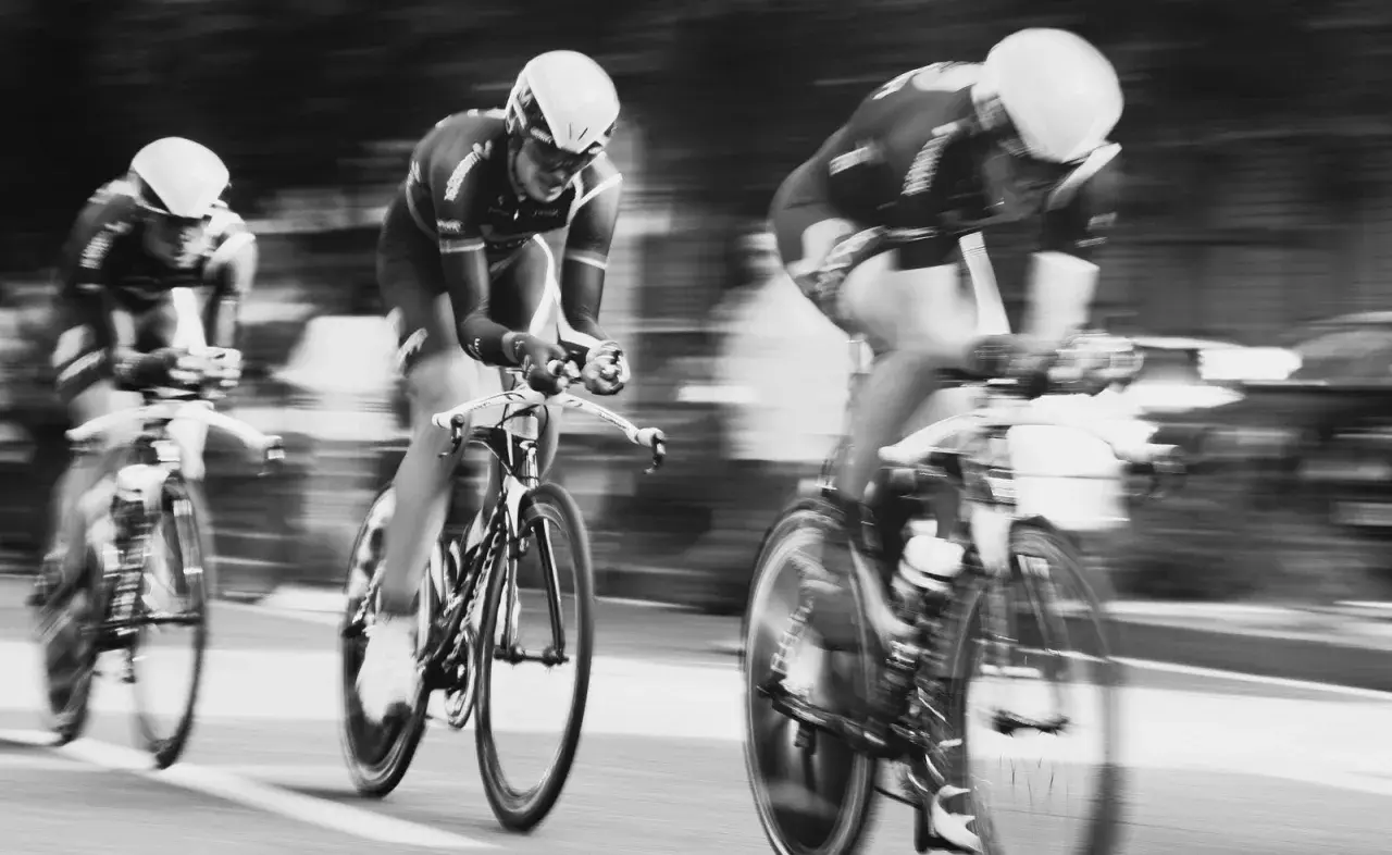 Drei Radfahrer in voller Fahrt, ein Beispiel dafür, wie funktioniert die Tour de France. Die Bewegung ist durch die Unschärfe spürbar.