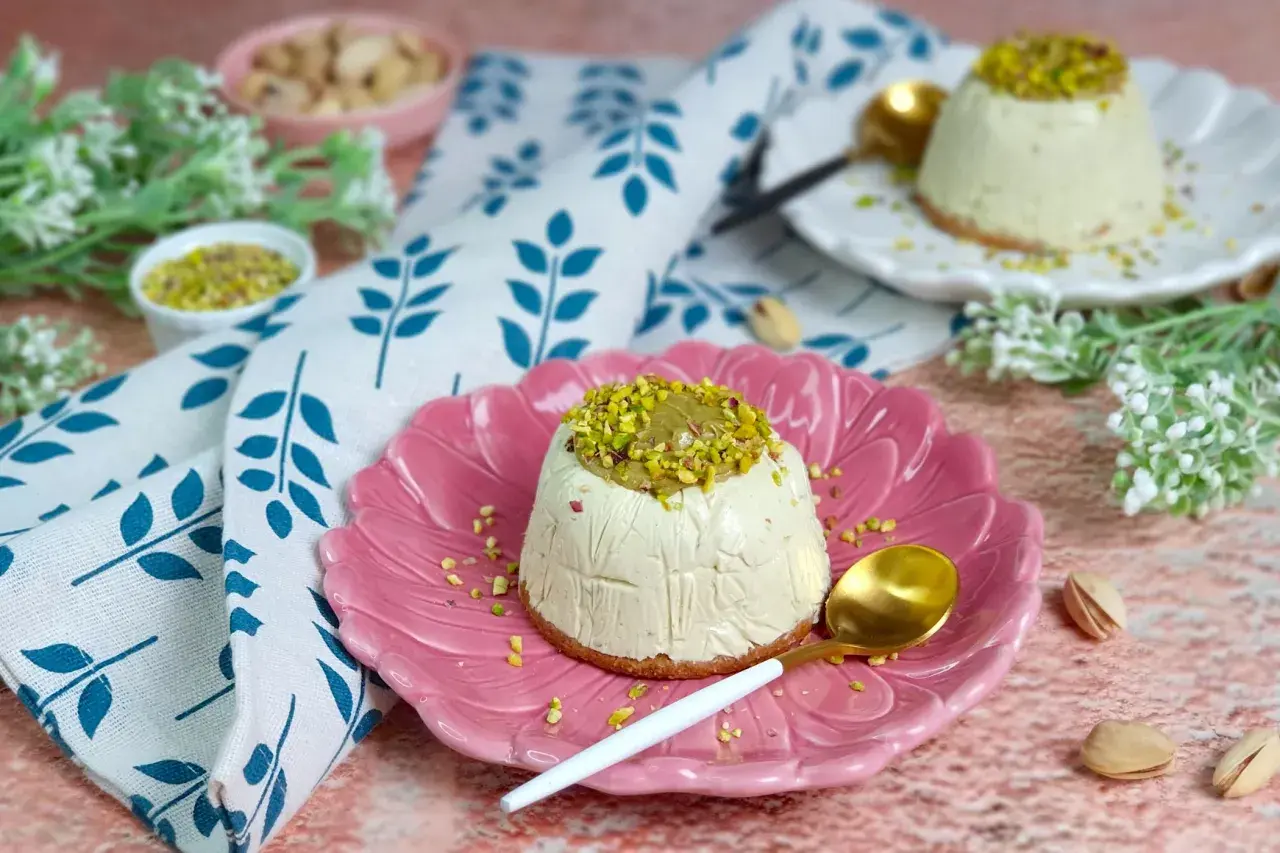 Delizioso semifreddo al pistacchio, guarnito con granella e crema di pistacchi, servito su un piatto rosa.