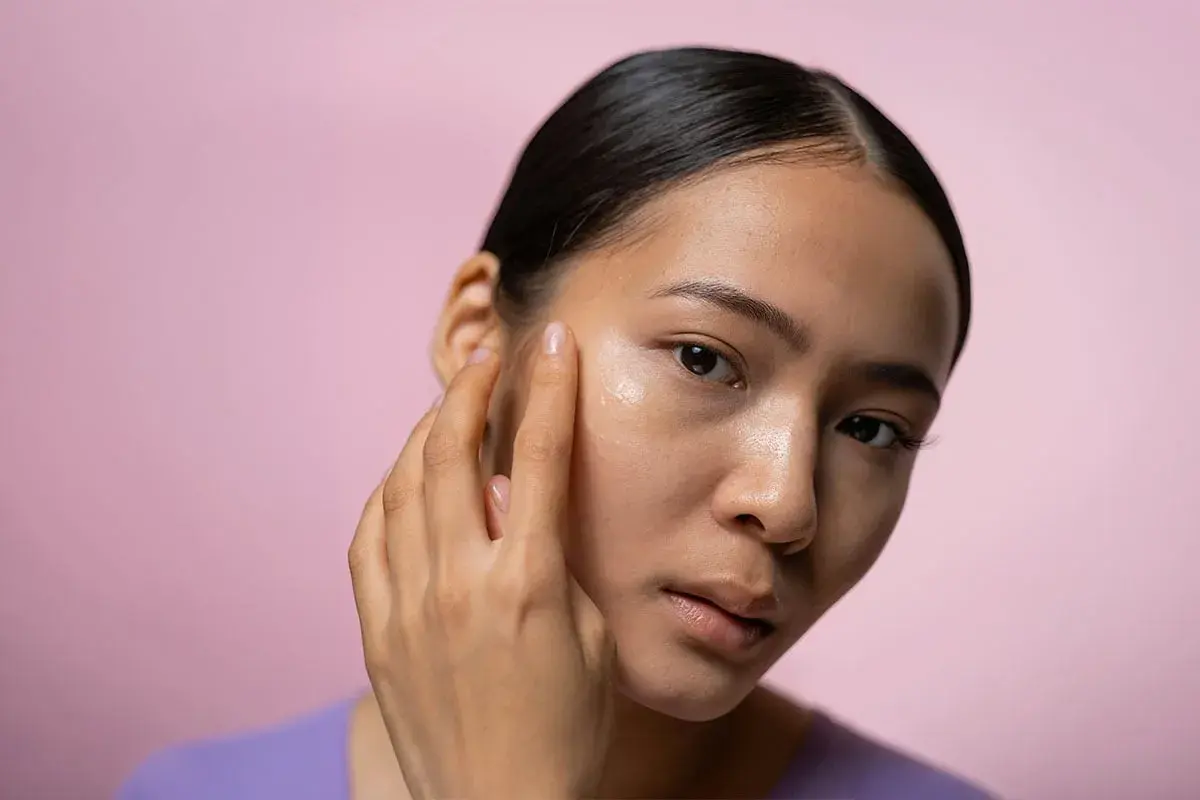 En kvinna applicerar en kräm i ansiktet, kanske en retinolkräm för ett strålande retinol ansikte.
