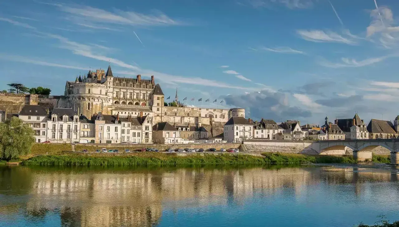Le majestueux château d'Amboise se dresse fièrement au-dessus de la Loire, ses tours et façades blanches reflétant la lumière du soleil sur l'eau paisible.