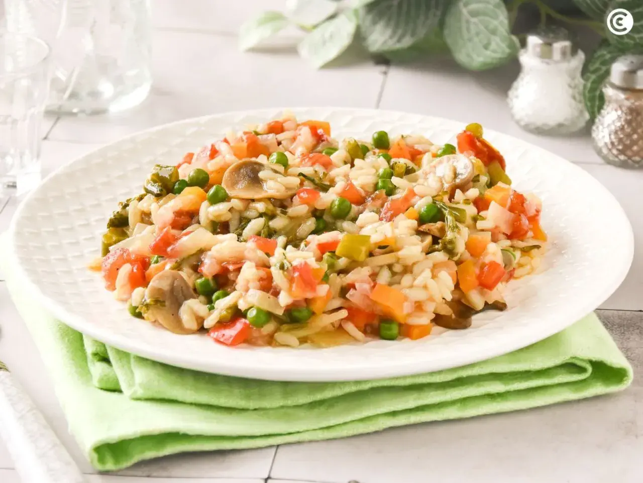 Un cremoso risotto de verduras con guisantes, champiñones y tomate.
