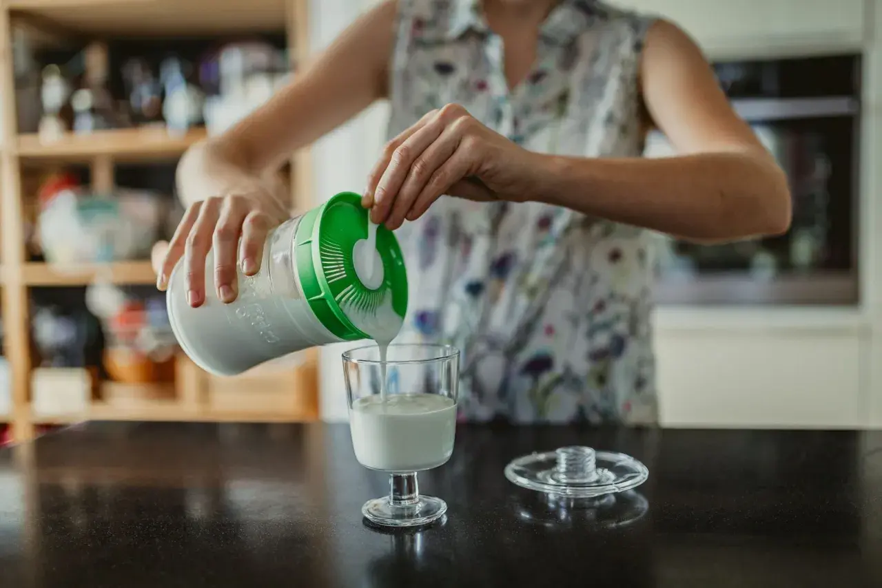 Persona sirve kéfir en un vaso. ¿Cuándo tomar kéfir antes o después de las comidas?