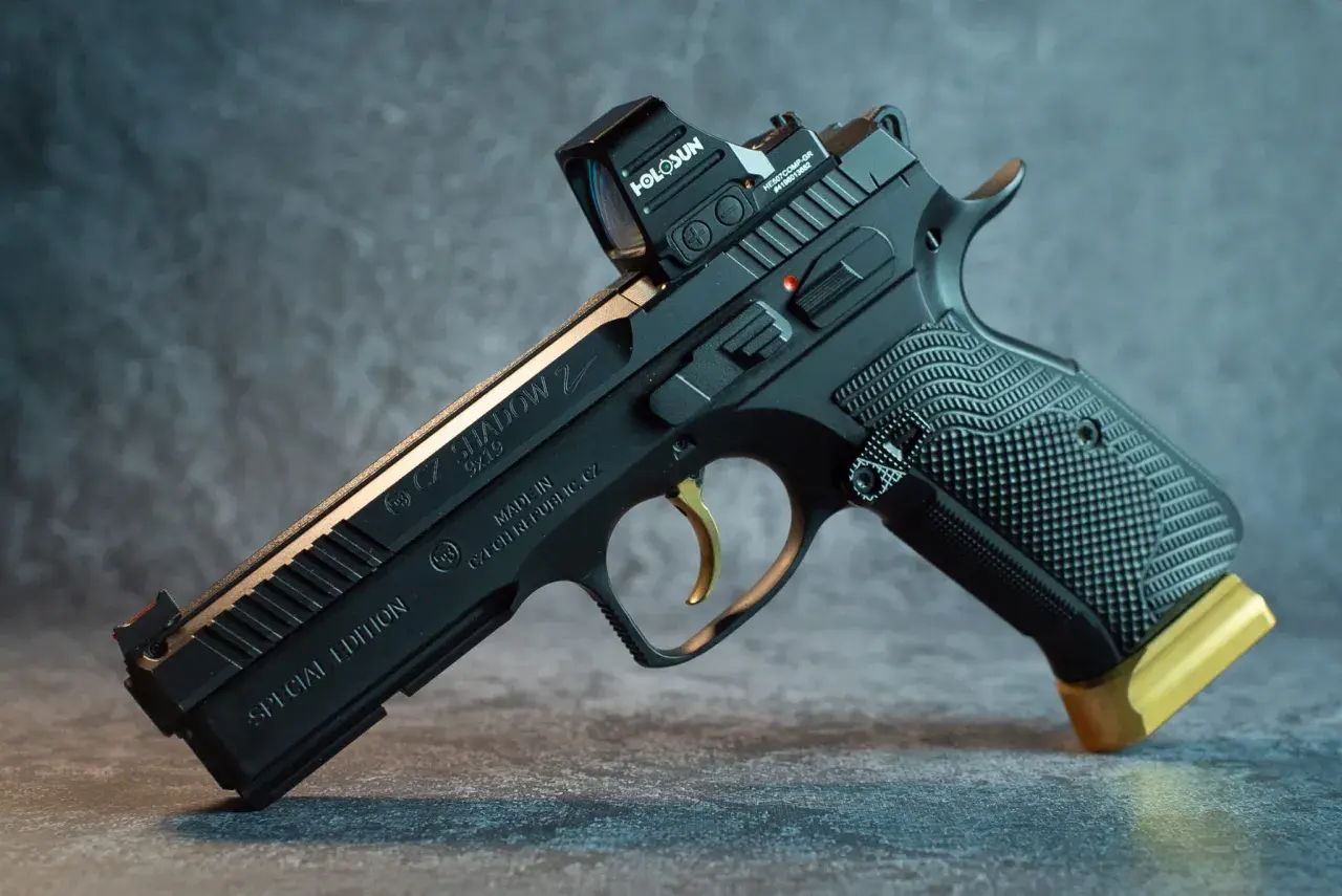 Czarny pistolet CZ Shadow 2 Special Edition z celownikiem Holosun i złotym przedłużeniem magazynka. Ten pistolet sygnałowy to marzenie kolekcjonera.