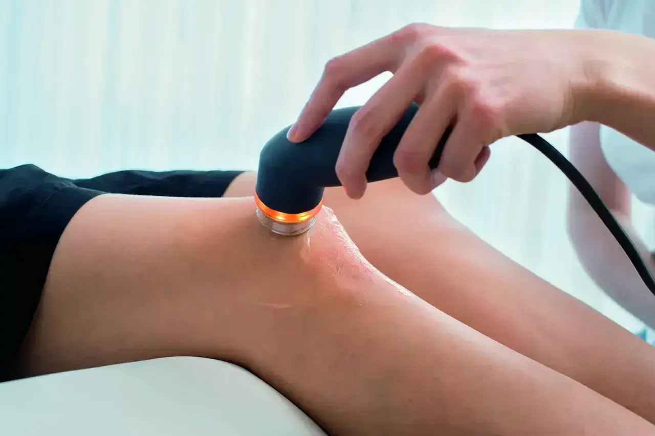 Fizjoterapeuta wykonuje zabieg ultradźwiękami na kolanie pacjenta. Należy pamiętać o ultradźwięki przeciwwskazania.