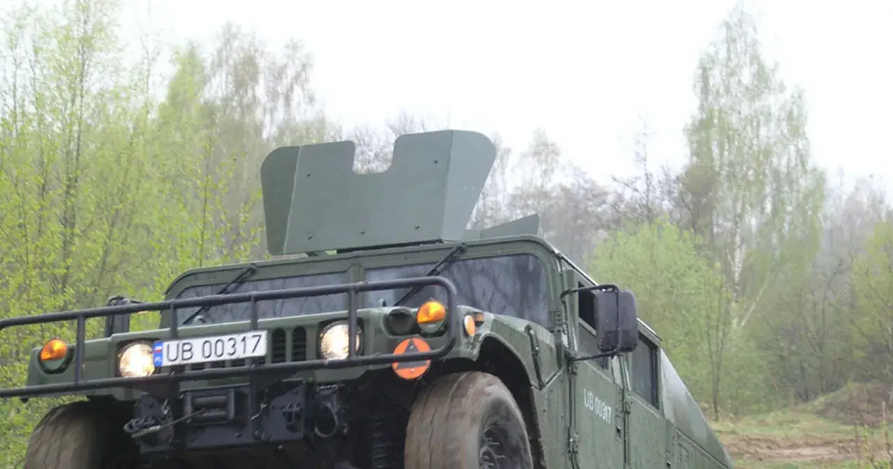 Zielony humvee z tablicą rejestracyjną UB 00317 jedzie przez las.