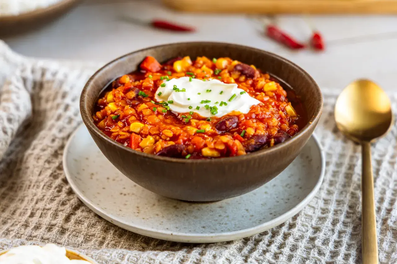 Herzhaftes Chilli sin Carne mit Mais, Bohnen und Linsen, garniert mit einem Klecks Sauerrahm und Schnittlauch.