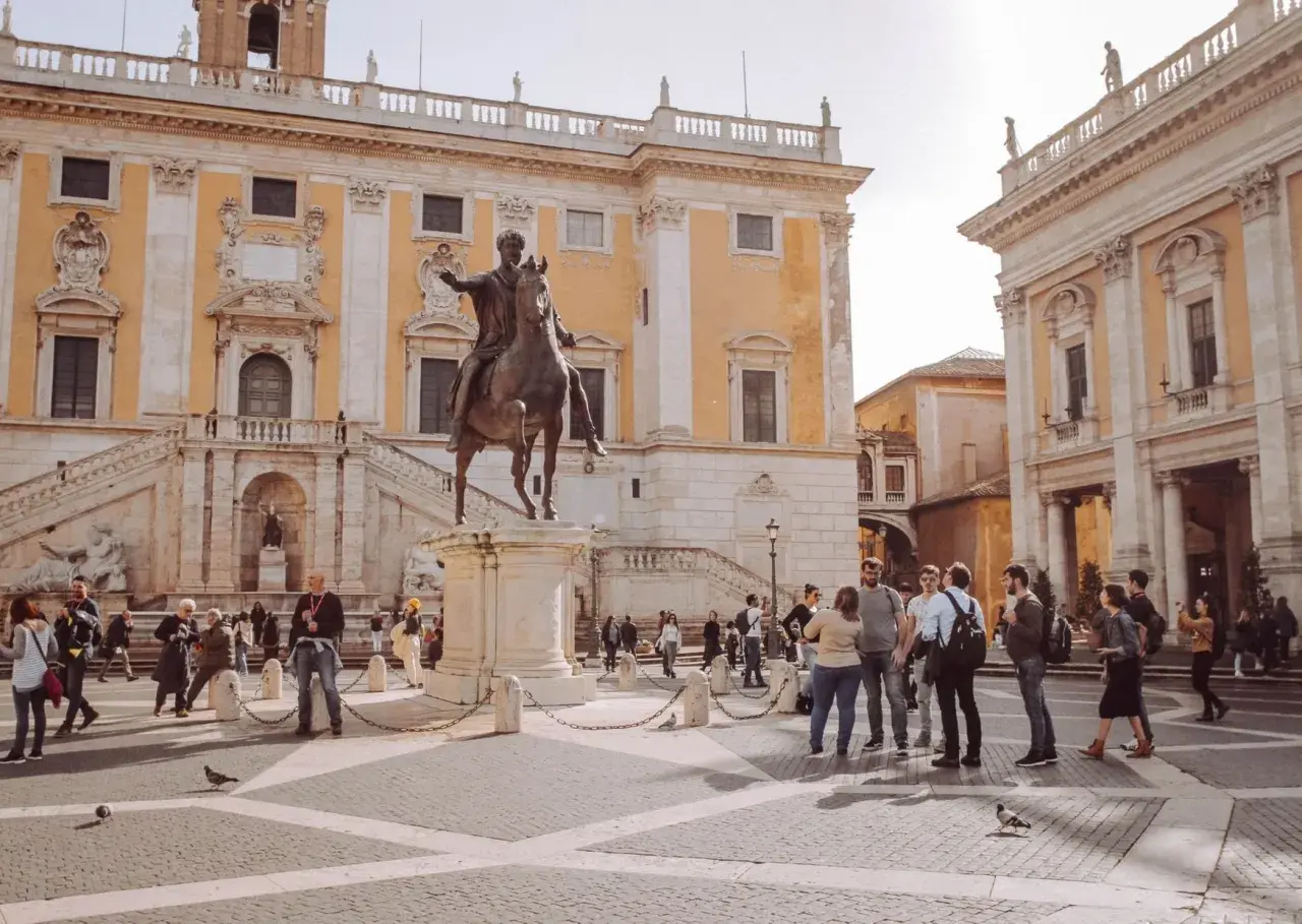 Piazza del Campidoglio a Roma, con la statua equestre di Marco Aurelio e turisti che ammirano l'architettura rinascimentale.