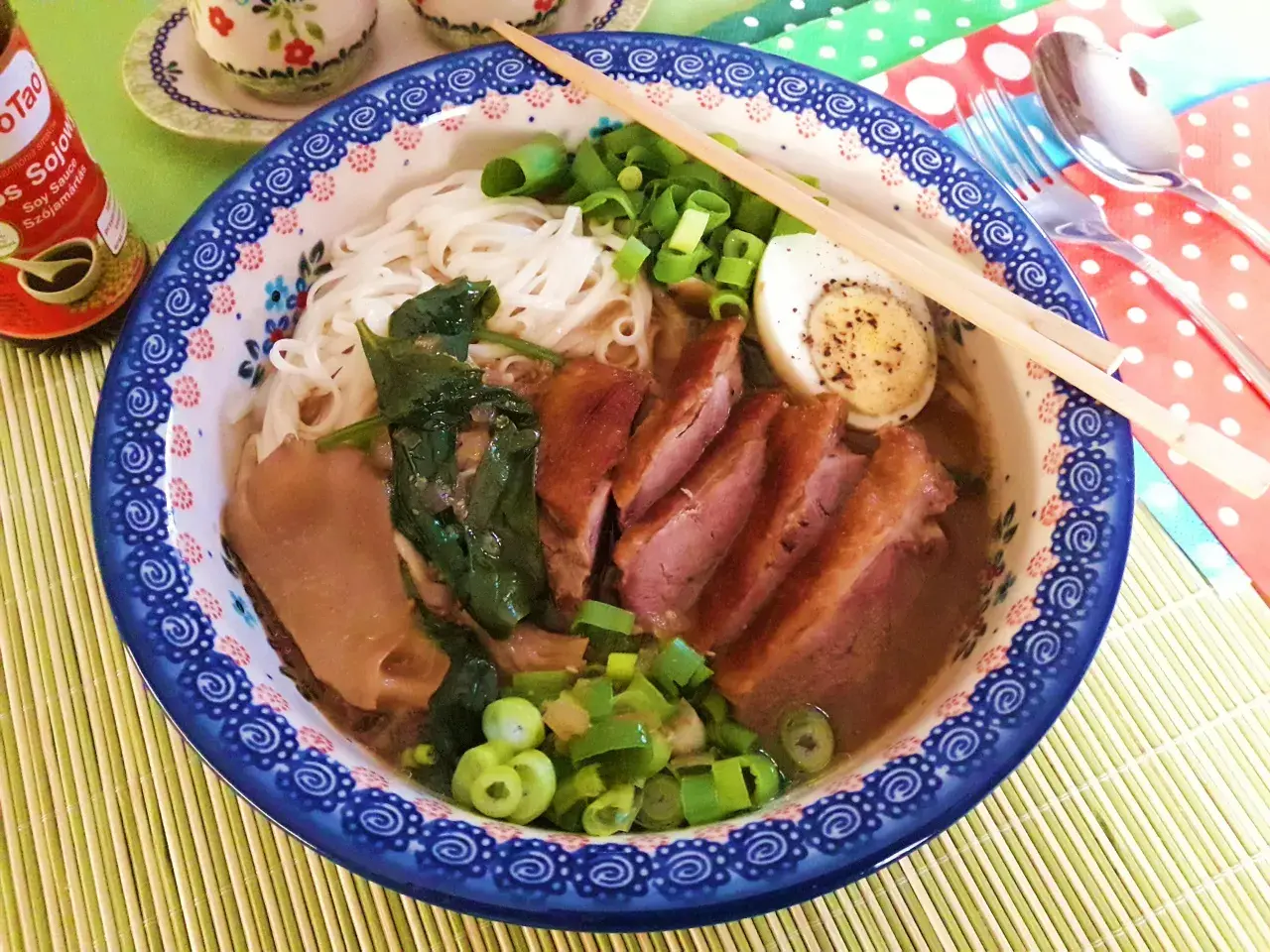 Aromaticzny ramen z kaczki z makaronem ryżowym, jajkiem na twardo, szpinakiem i szczypiorkiem.