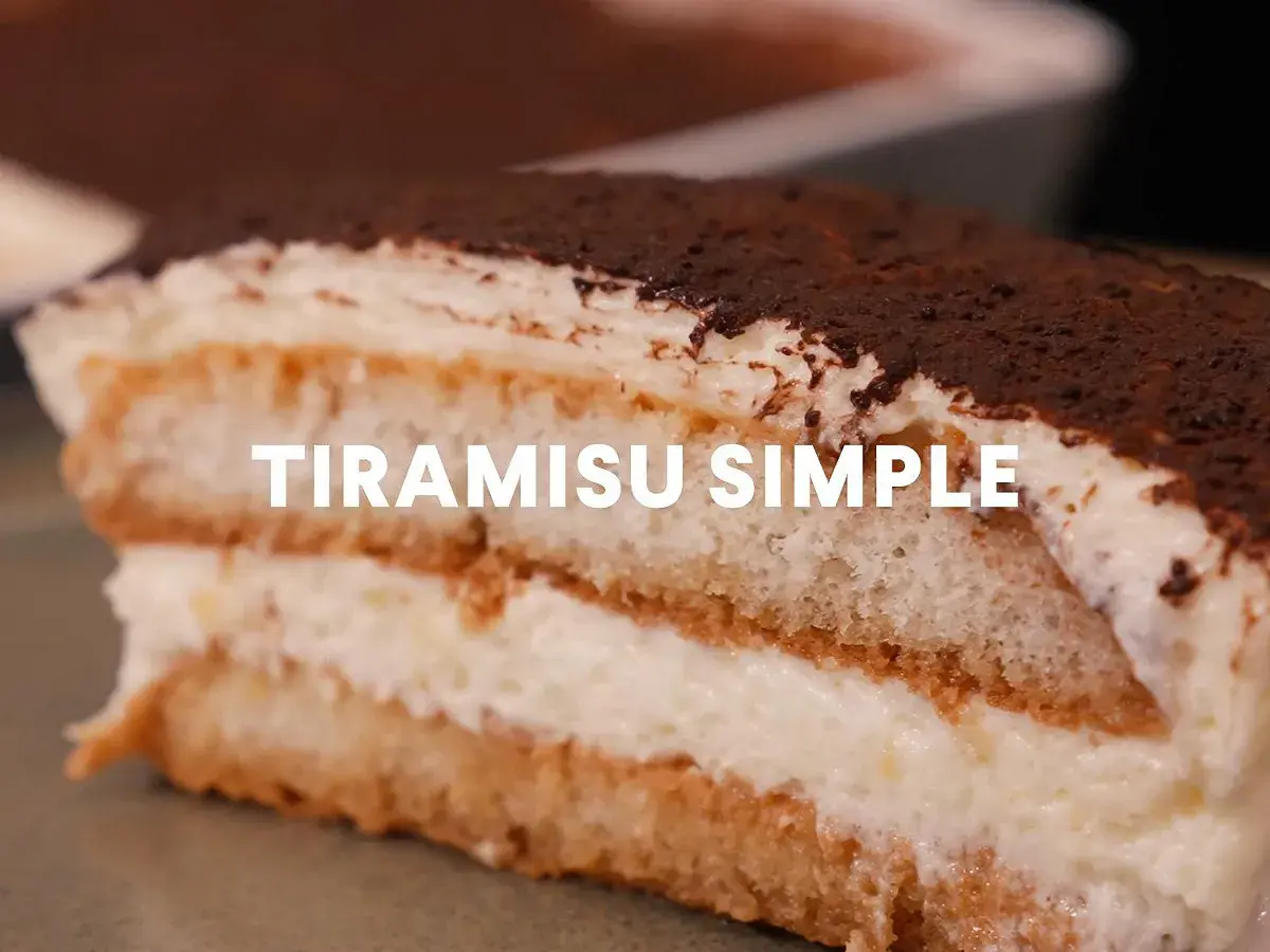 Une part généreuse de tiramisu simple, parfait pour 10 personnes, avec ses couches de biscuits imbibés et de crème onctueuse, saupoudré de cacao.