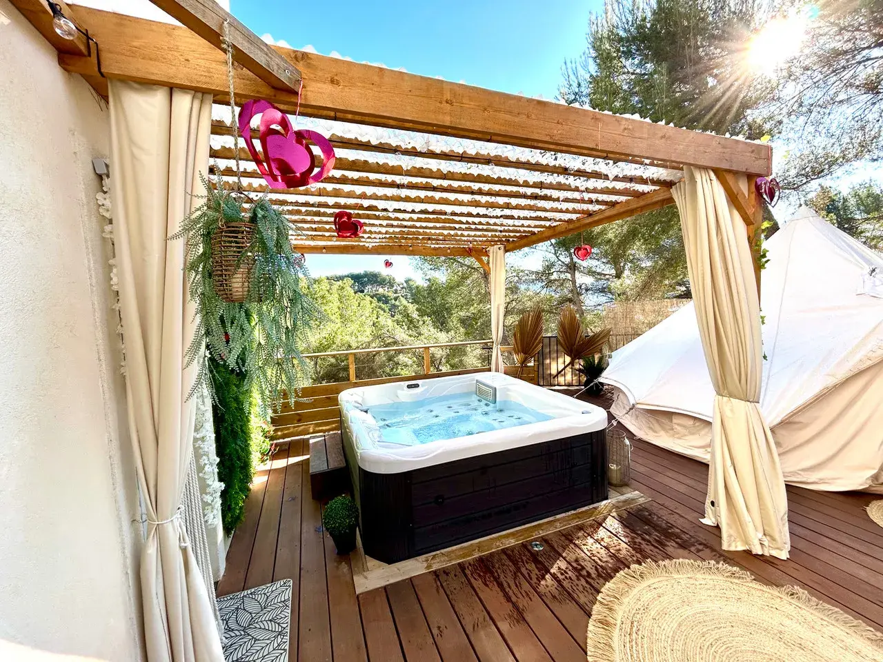 Jacuzzi extérieur sous pergola, décoré de cœurs, près d'une yourte dans les Alpes-Maritimes. Détente et nature.