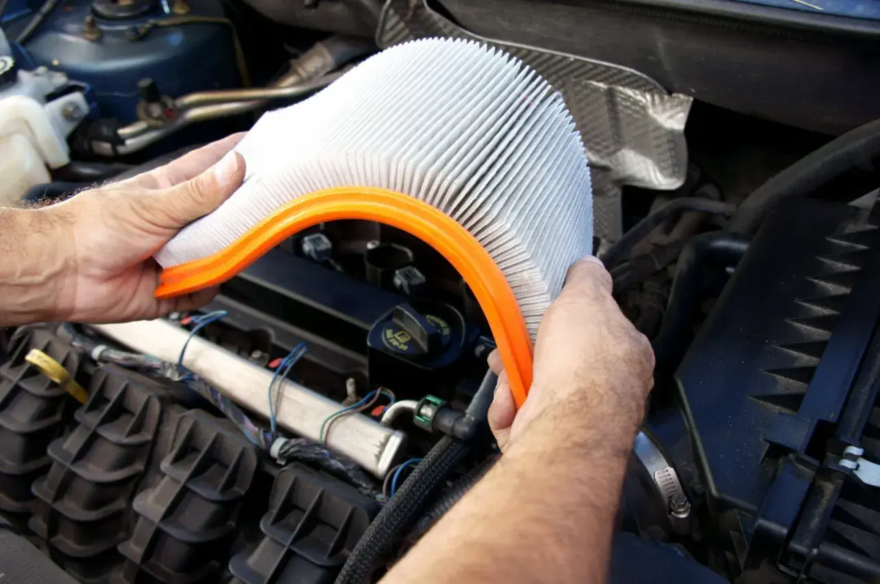 Main tenant, quand changer filtre à air. Un homme tient un filtre à air de voiture propre, prêt à le remplacer dans le compartiment moteur.