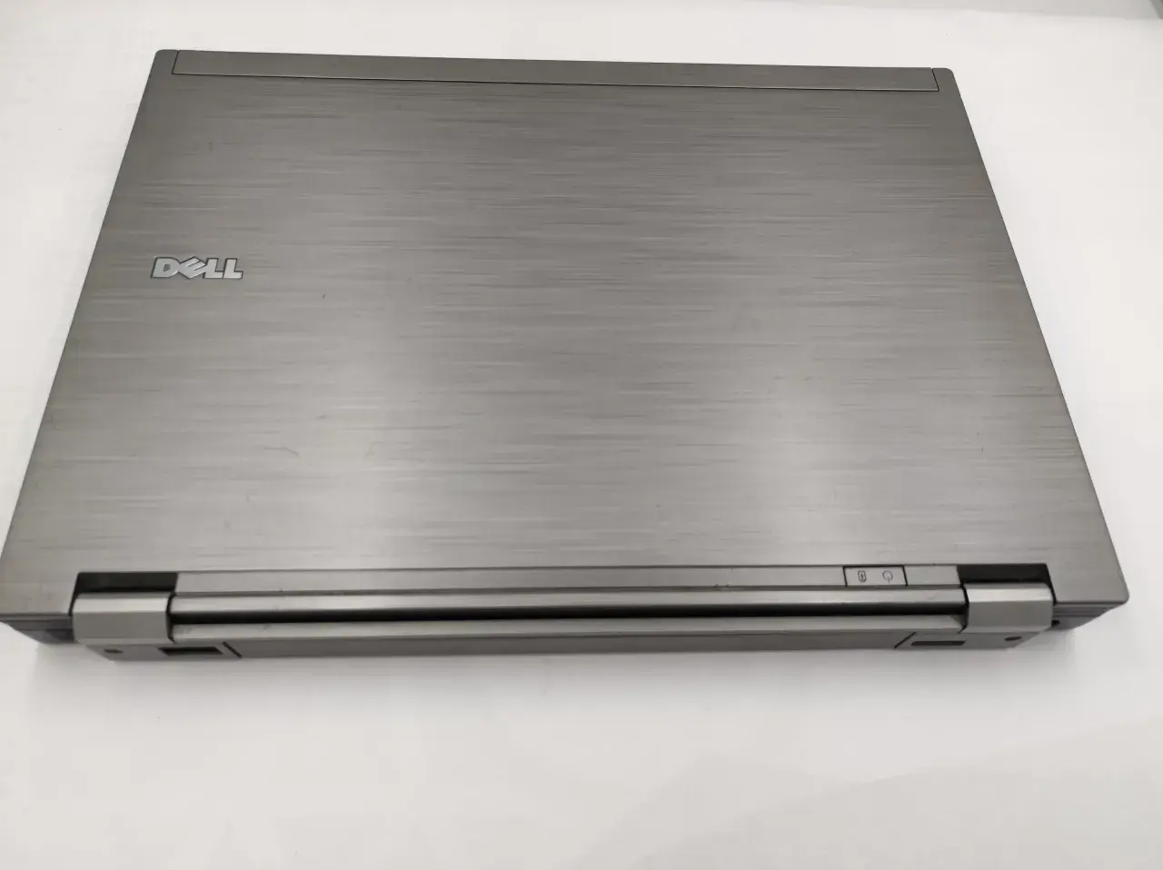 Zamknięty laptop Dell Latitude E6410, z widocznym logo Dell i przyciskami zasilania. Idealny do sprawdzenia dell latitude e6410 specyfikacja.