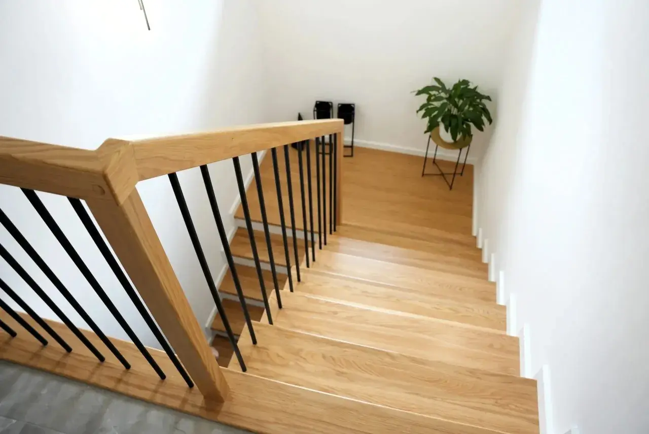 Nowe schody drewniane z czarnymi balustradami. Zobacz, jak zrobić schody drewniane, by nadać domowi ciepły i nowoczesny wygląd.