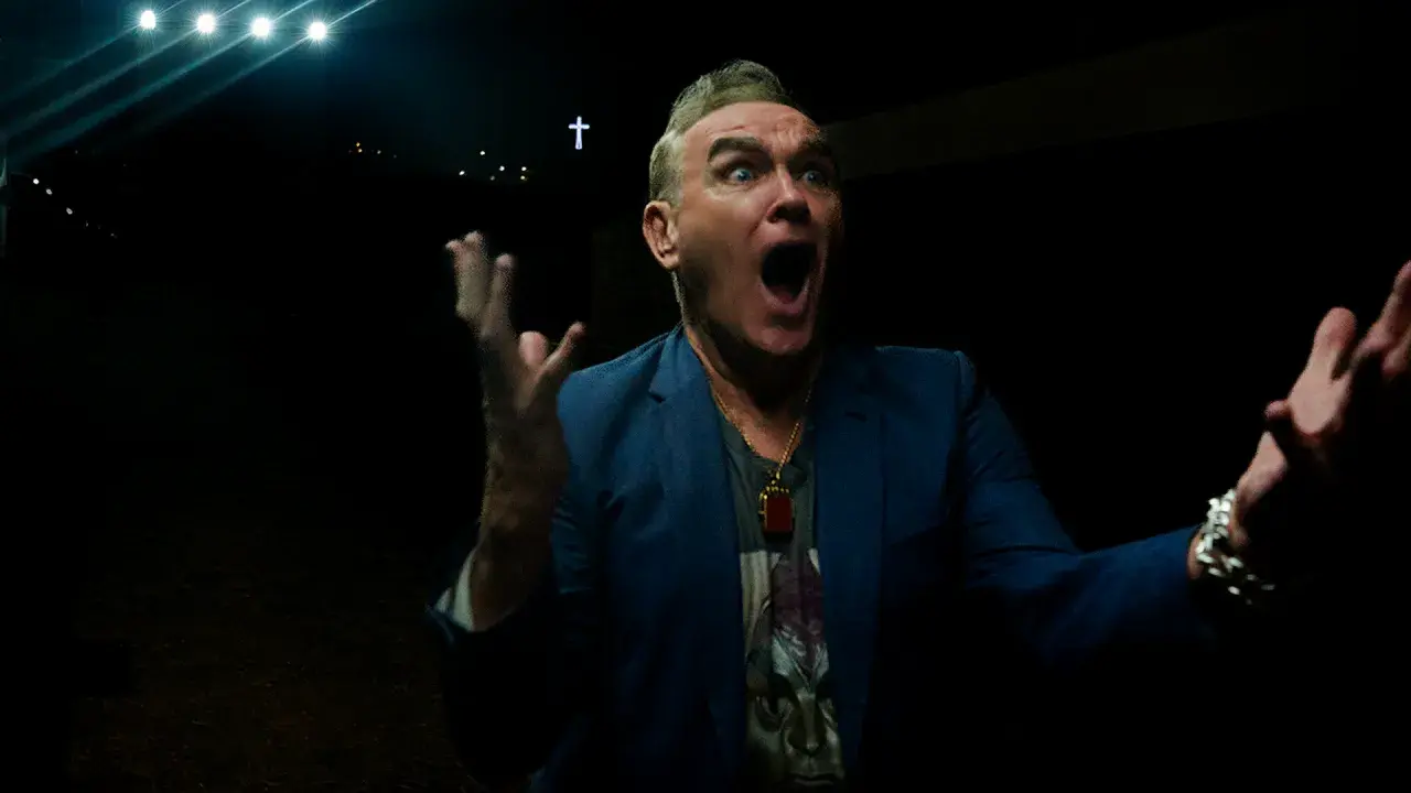 Morrissey en Zaragoza, con gesto dramático y las manos alzadas, bajo luces y una cruz.