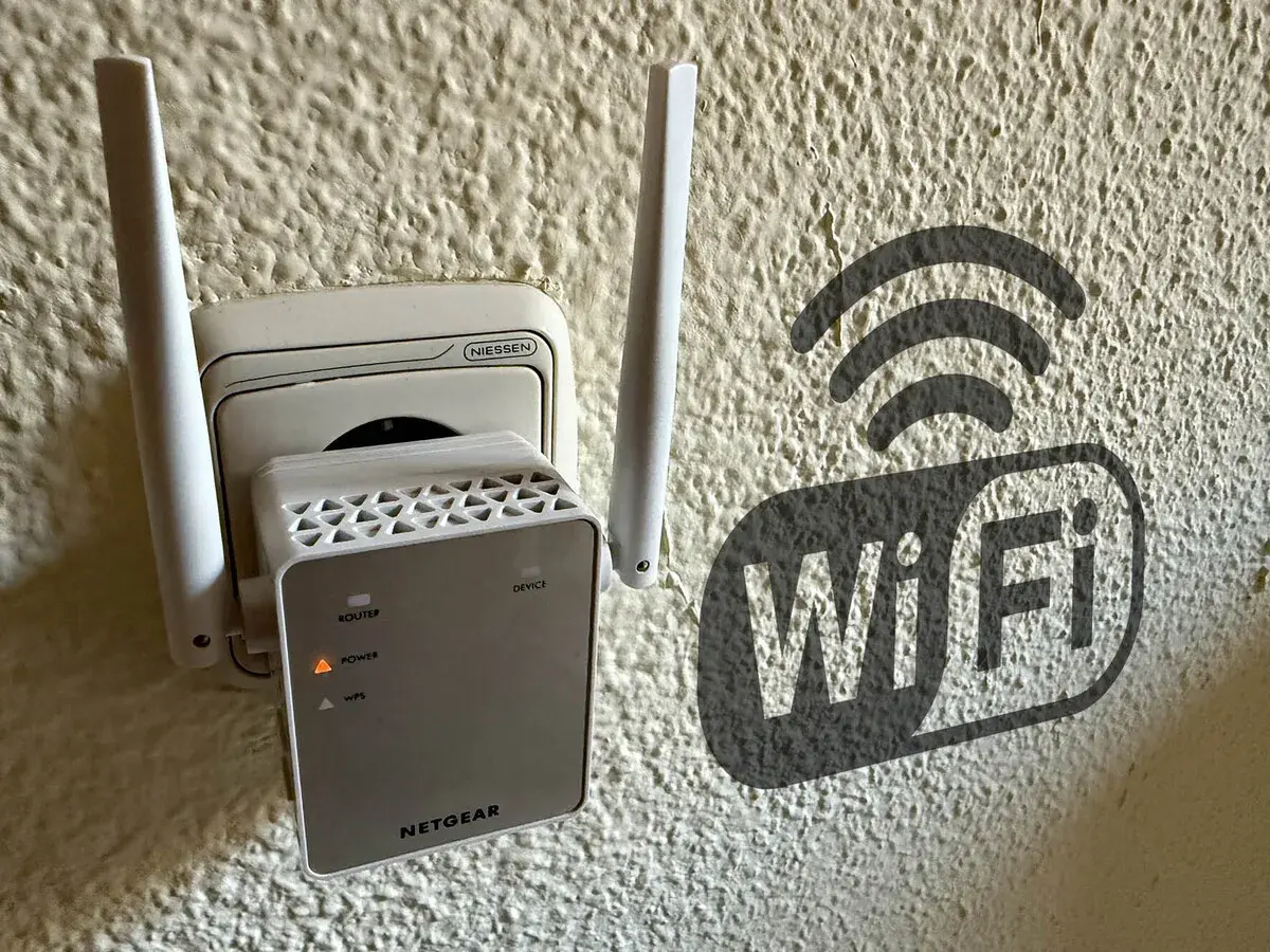 Extensor de red **wireless WAN** enchufado a la pared, con un símbolo de Wi-Fi al lado.