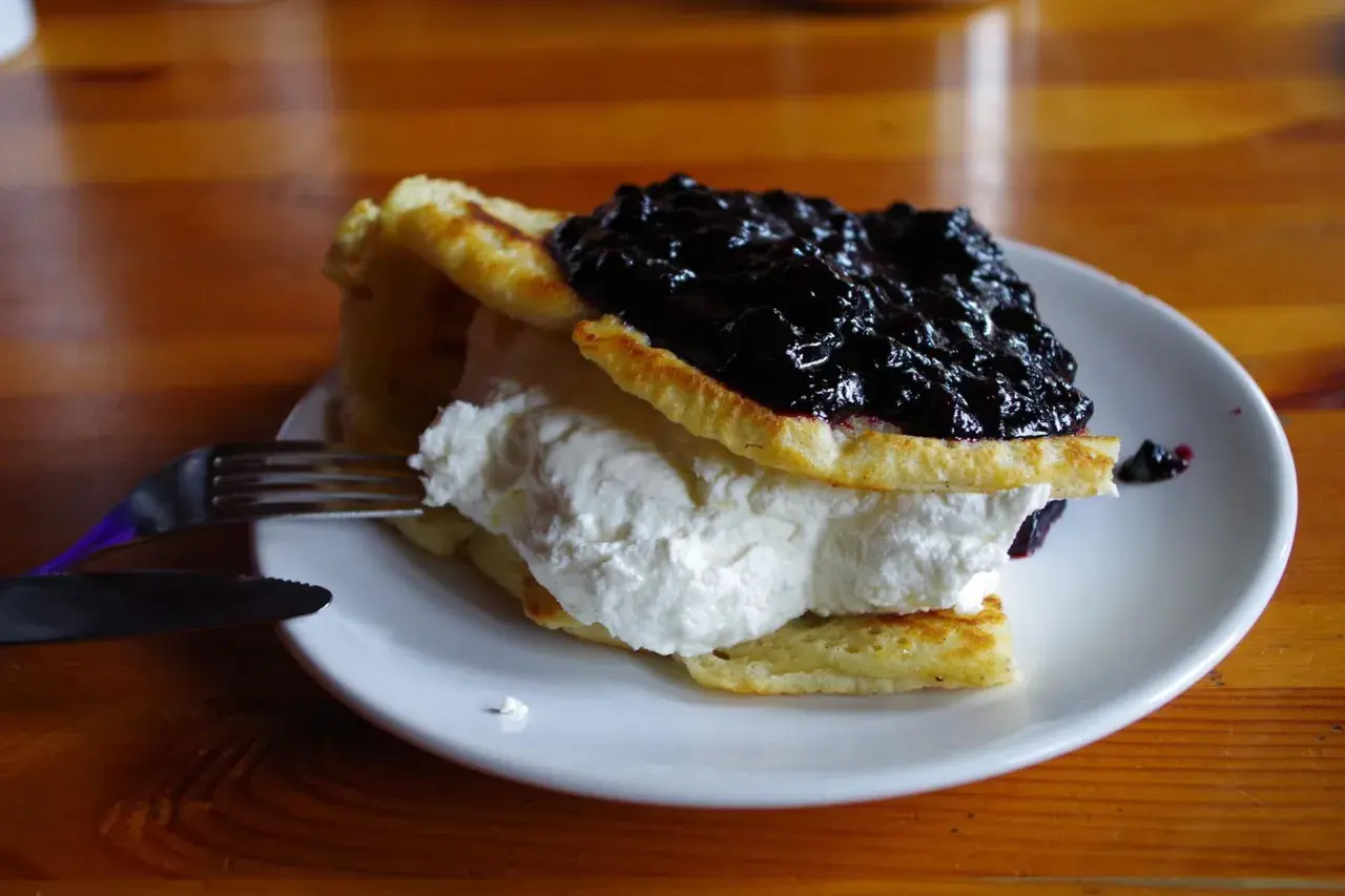 Puszyste naleśniki z bitą śmietaną i jagodami, idealne do menu chatki górzystów.