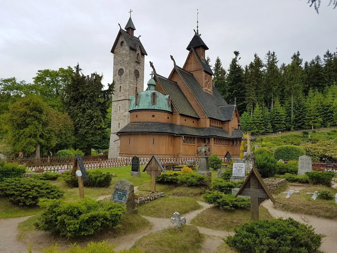 Drewniana świątynia Wang w Karkonoszach, otoczona cmentarzem i lasem.