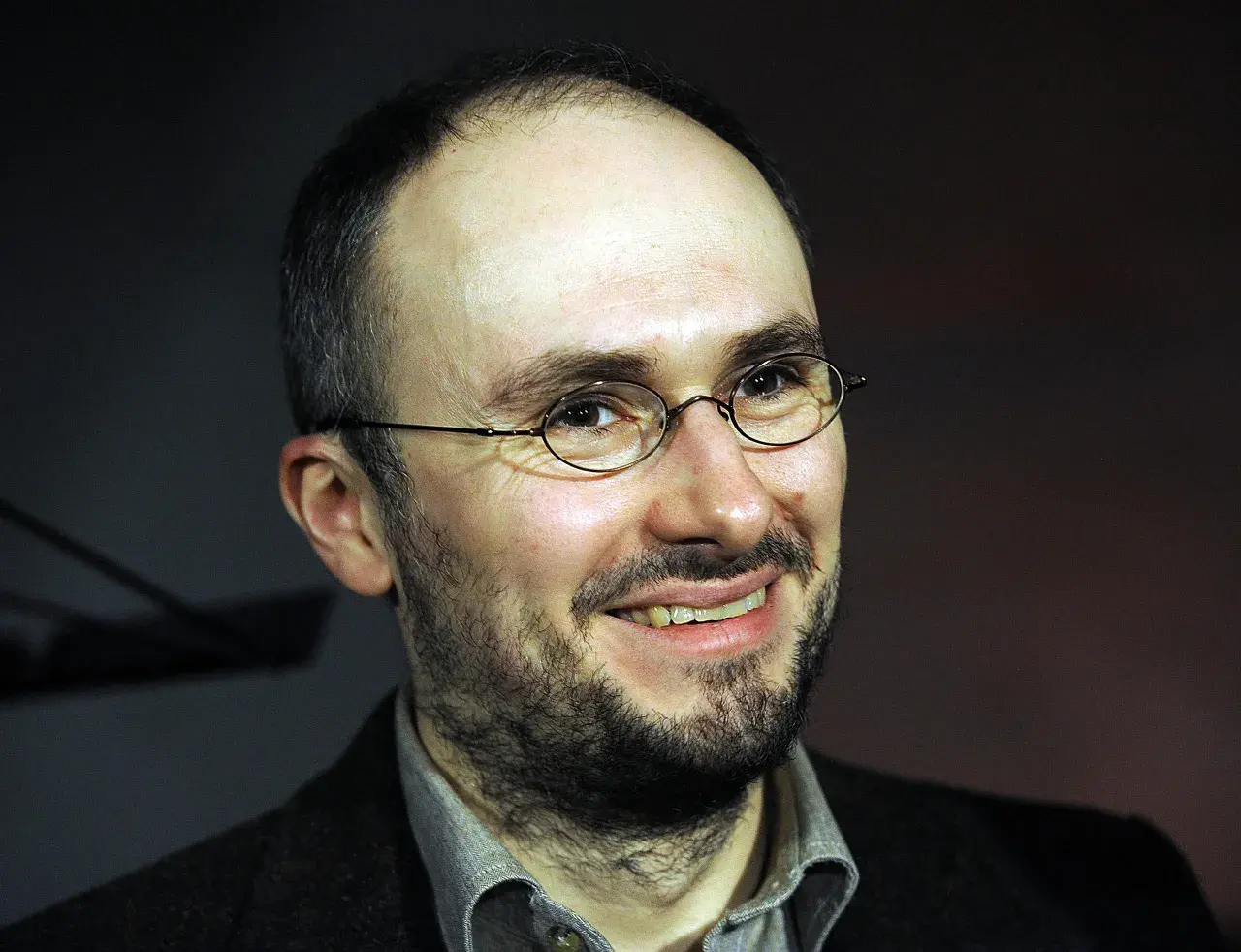 Uśmiechnięty mężczyzna w okularach, z zarostem. Sebastian Krajewski, którego życie prywatne budzi zainteresowanie, wygląda na zrelaksowanego.
