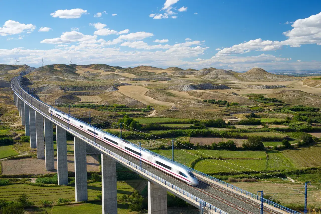 Schneller Zug auf einer Hochbahnbrücke, der die Landschaft von Deutschland nach Spanien durchquert.