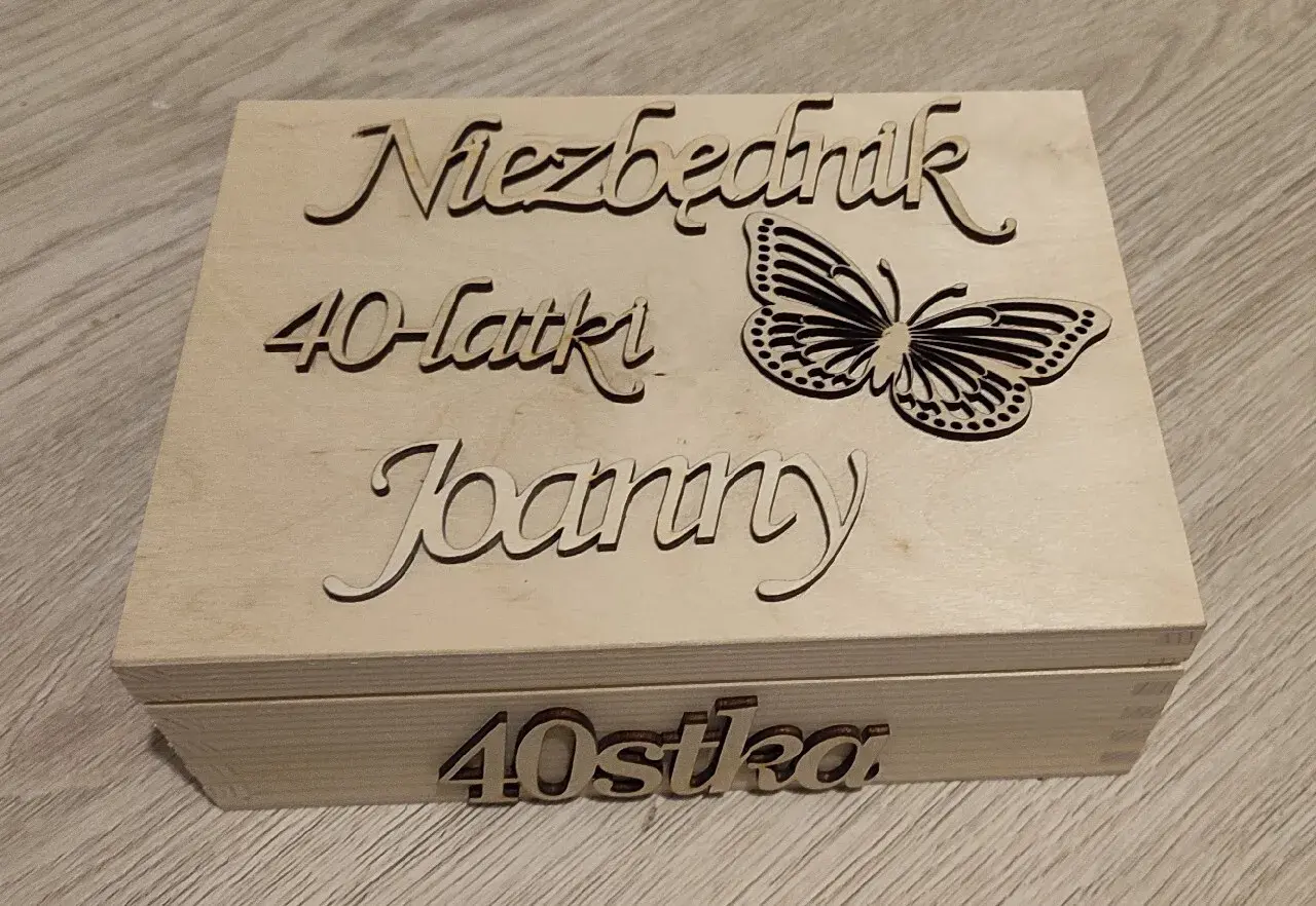 Drewniana skrzynka z napisem "Niezbędnik 40-latki Joanny" i motylem. Na froncie "40stka".