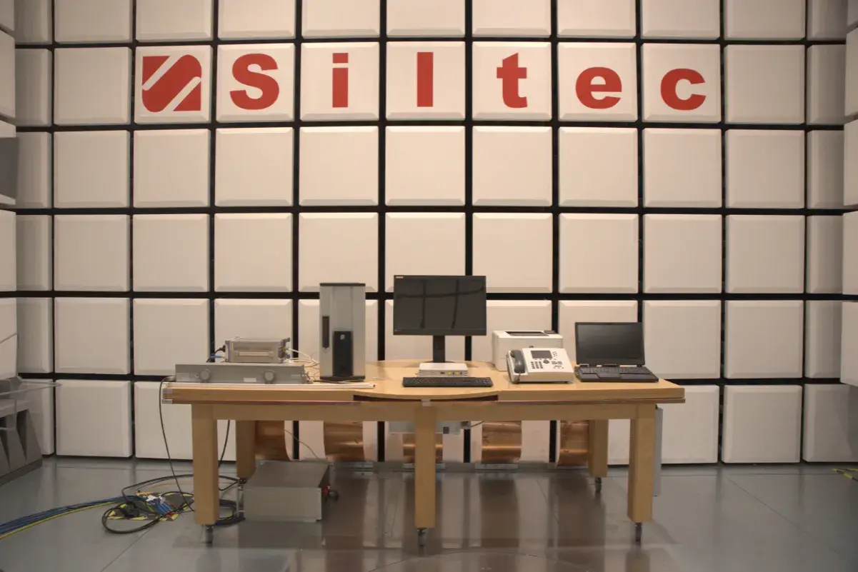 Laboratorium testowe z urządzeniami elektronicznymi i logo "Siltec". W tle ściana z paneli akustycznych, chroniąca przed zakłóceniami, jak podczas burzy (tempest).