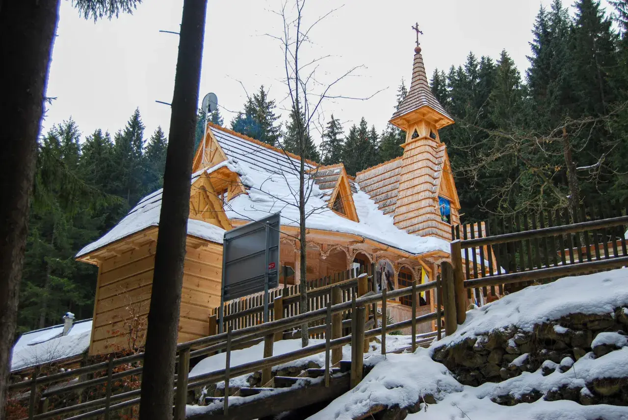 Drewniane sanktuarium maryjne na Wiktorówkach w zimowej scenerii, otoczone lasem iglastym.