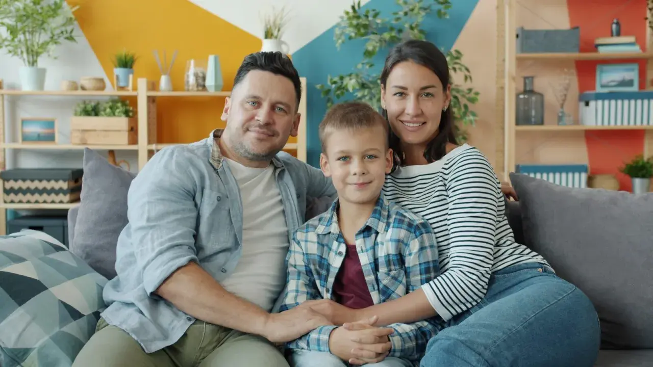 Szczęśliwa rodzina: tata, mama i syn siedzą na kanapie. Choć nie da się określić, ile kosztuje dziecko, miłość i radość są bezcenne.